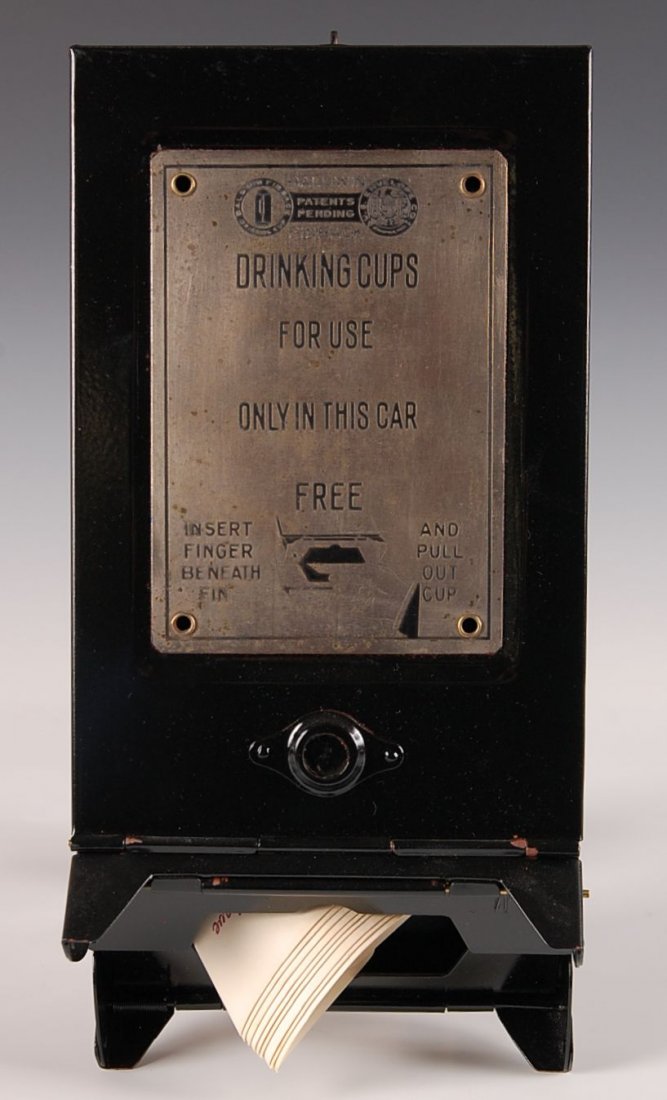 NORFOLK & WESTERN RR DRINKING CUP DISPENSER: Black painted steel casing with riveted front plaque, having printed 'Baldwin Finback, Drinking Cups for use only in this car, Free,' etc. Includes nine paper cups with N&W logo. Measures 12 x 6 x 2.7