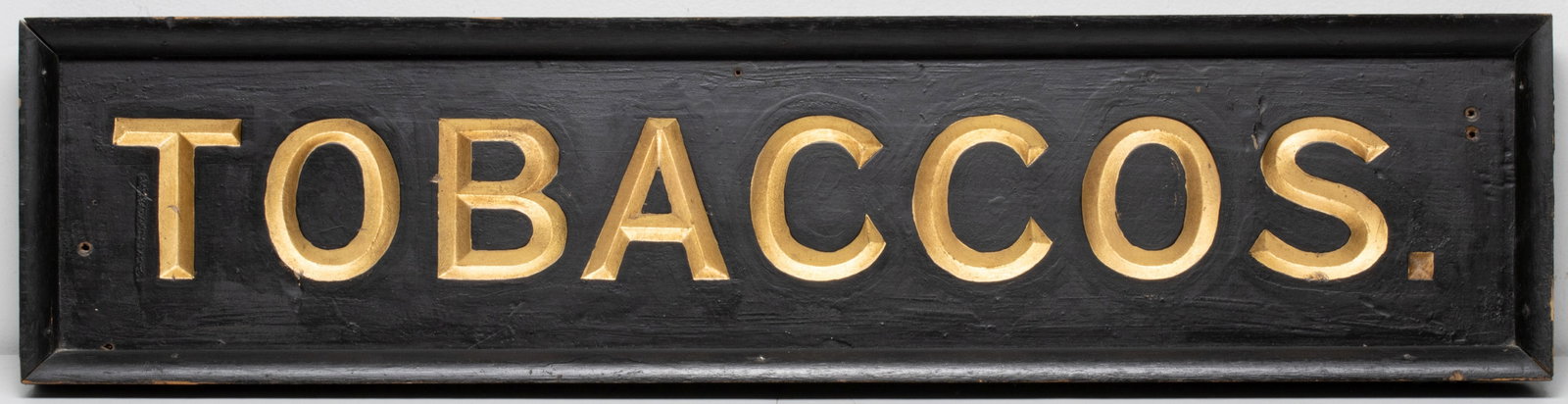 A 'TOBACCOS' WOOD SIGN WITH GILT RECESSED LETTERING: The self-framed wood sign is circa 1900. Measures 32 x 8 inches. Without proof of exemption, be aware that internet sales tax applies to all Internet transactions and local sales tax may apply to loca