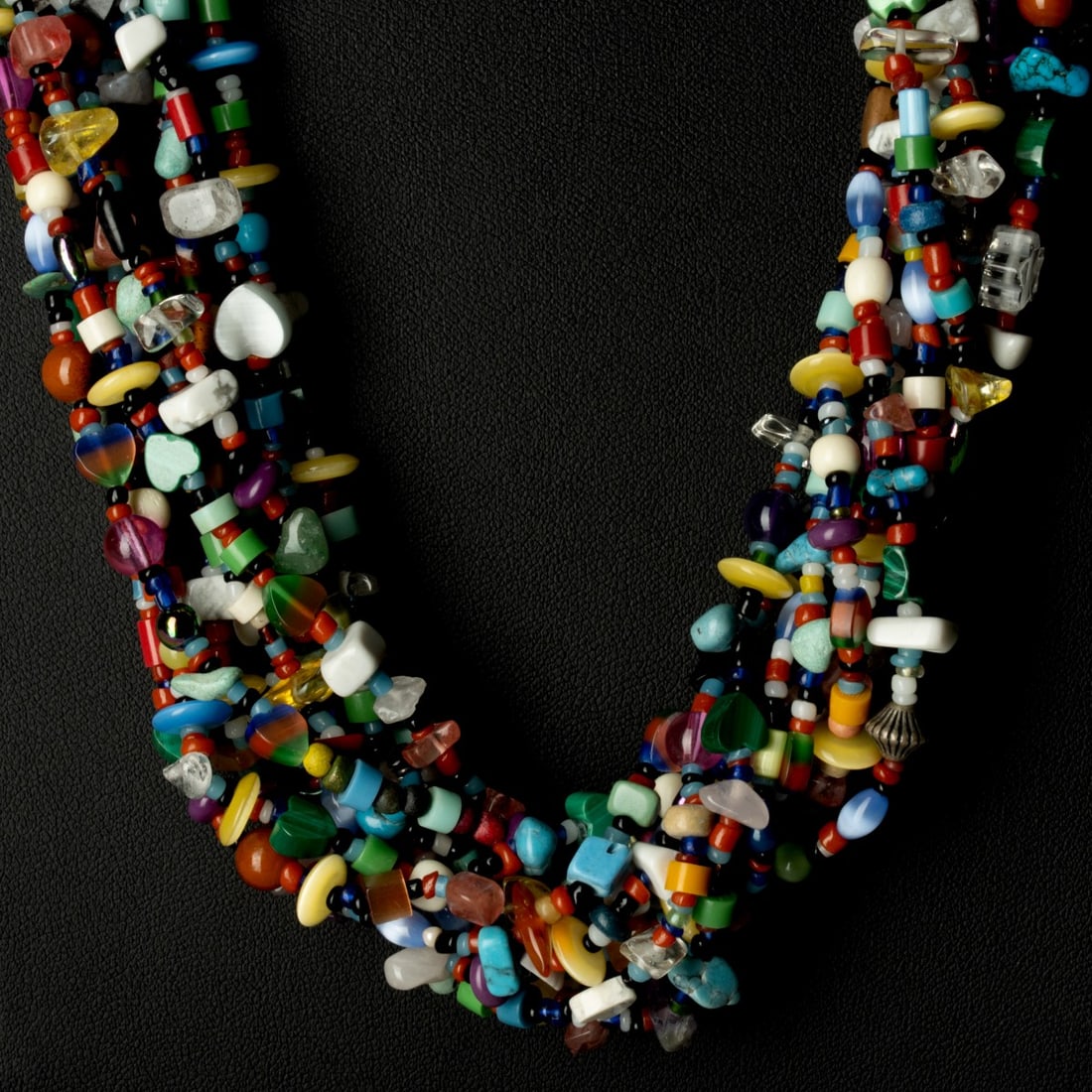 A PUEBLO TEN STRAND SEMI PRECIOUS STONE HEISHI NECKLACE: Featuring red coral beads and assorted multi-color gemstone or trade beads and discs, finished with silver cones and a hook-and-eye clasp, Turquoise, Malachite, Lapis, many varieties of quartz, multi