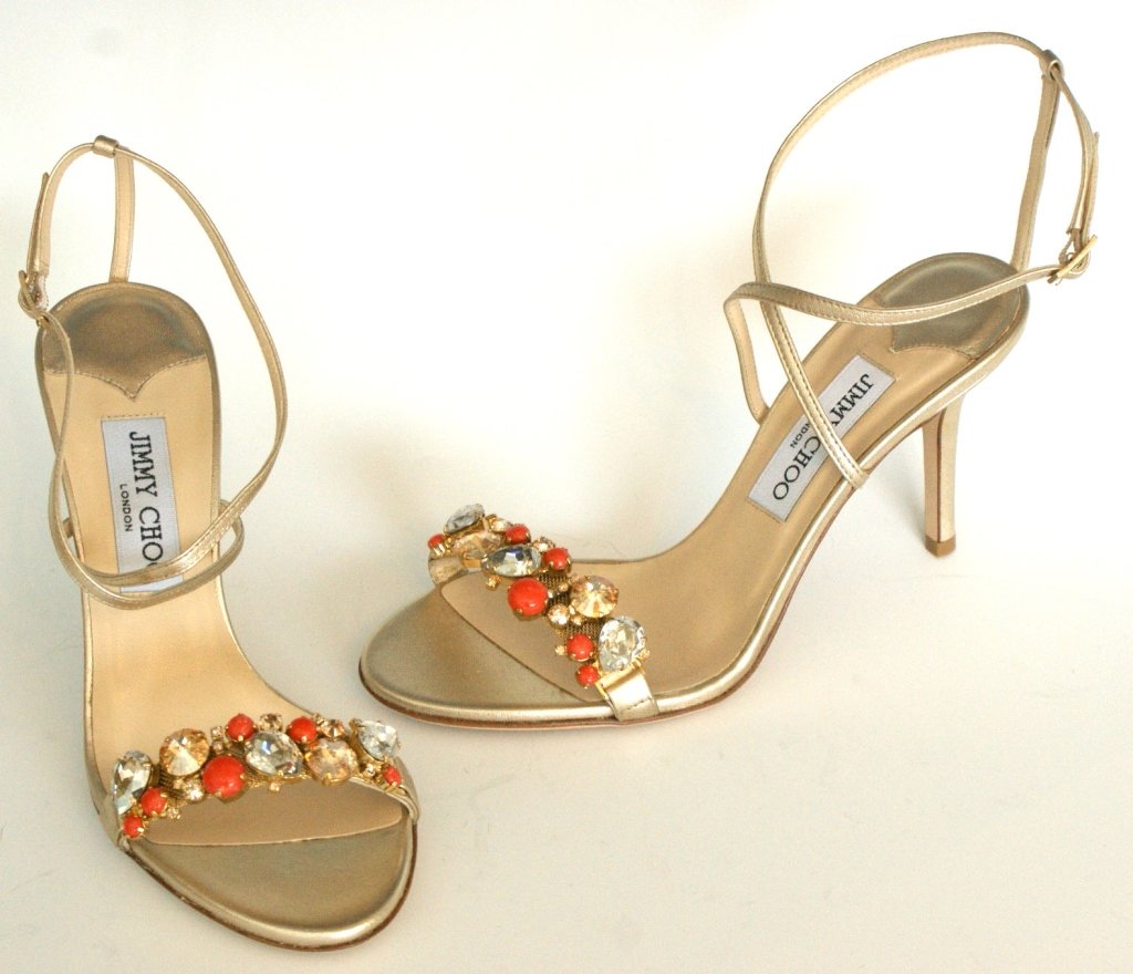 JIMMY CHOO SANDALS w GEMSTONES IN GOLD, SZ 7: Metallic Napa gold with clear, amber and coral faceted and cabochon cut gemstones across toe strap. Original box and dust bag. Size 7 (37.5) with heel height of 3 1/4 inches. New, never worn.