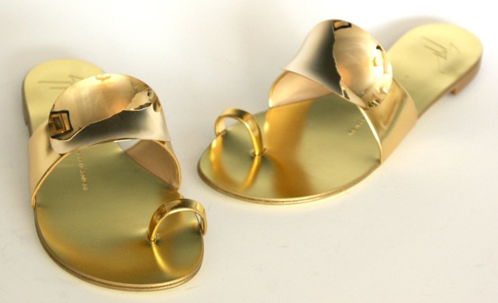 GIUSEPPE ZANOTTI GOLD SHIELD THONG SANDAL, SZ 7: Gold strap adorned with convex oval, gold shield. Leather forms padded sole and toe ring. Slip-on style. Flat stacked heel. Made in Italy. Original box and dust bag. Size 7 (37.5) New, never worn.