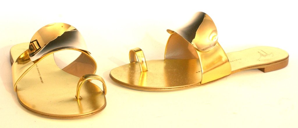 GIUSEPPE ZANOTTI GOLD SHIELD THONG SANDAL, SZ 7: Gold strap adorned with convex oval, gold shield. Leather forms padded sole and toe ring. Slip-on style. Flat stacked heel. Made in Italy. Original box and dust bag. Size 7 (37.5) New, never worn.