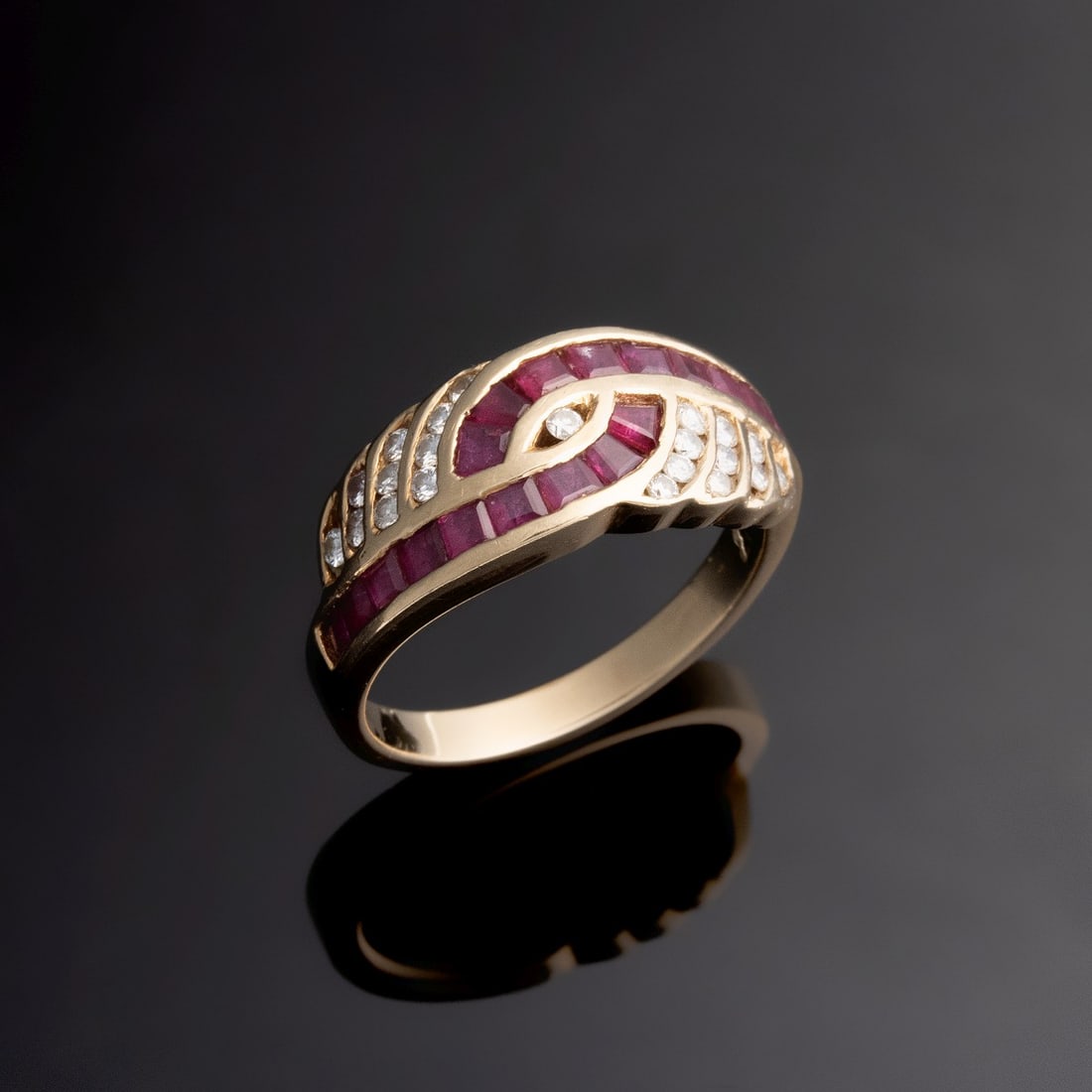 A LADY'S RUBY AND DIAMOND 14K GOLD FASHION RING: The sweeping ribbon-like bands of calibre step-cut channel-set rubies (10 each side) are accented by stepped curvilinear channels of round brilliant-cut diamonds. This asymmetrical and sculptural moun