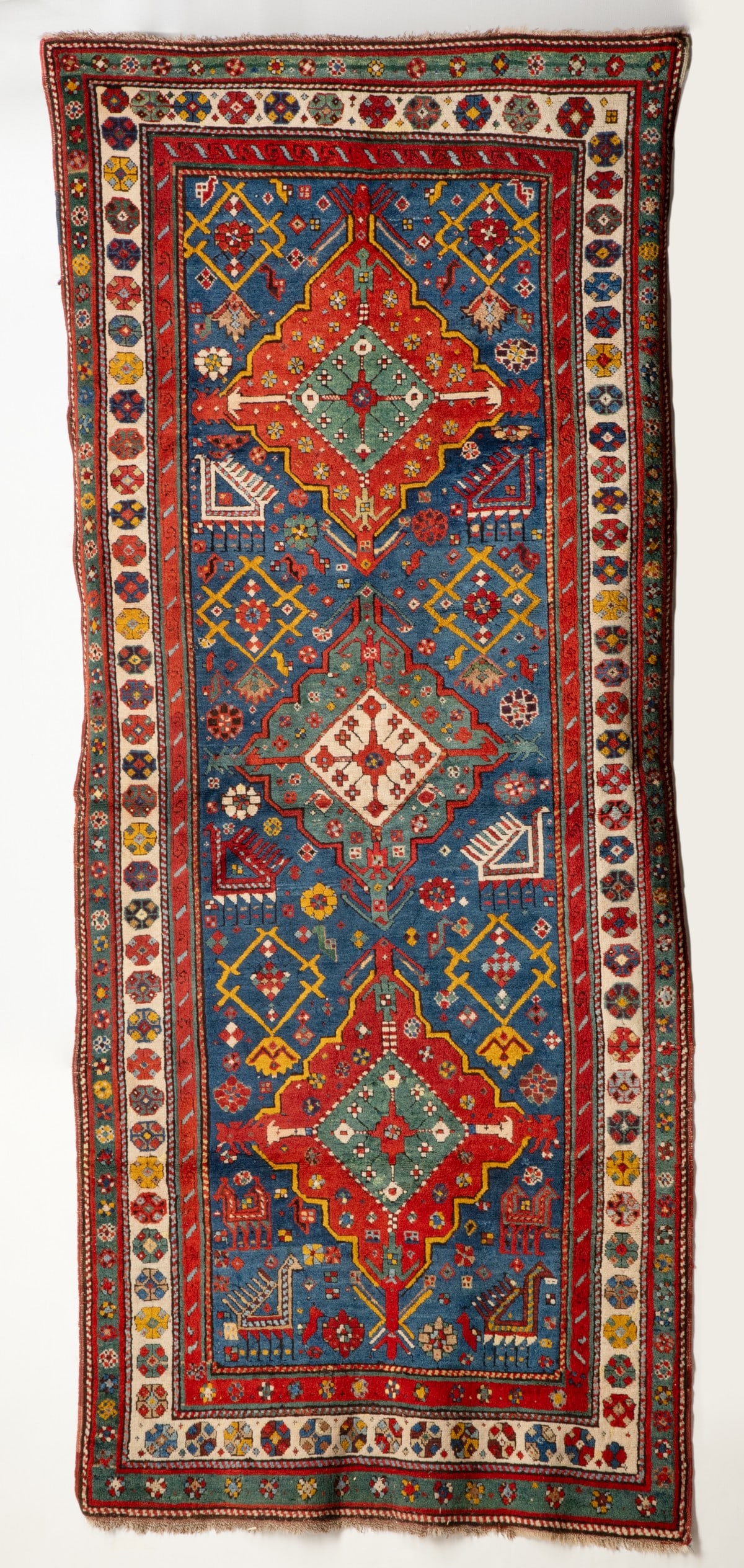 A FINE TALISH RUNNER, CIRCA 1880: The pale blue field with a central green and ivory lobed medallion between two similar red medallions, supported by rhombus medallions, ibex, flower heads and 'Akstafa' style peacocks within an ivory