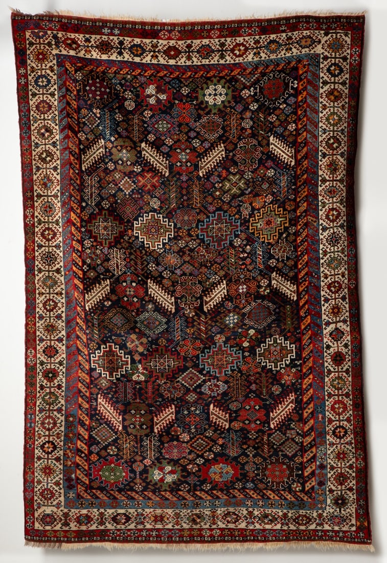 A FINE QASHQAI SHERKARLU RUG, LAST QUARTER 20TH C: The blue field with an allover design of stepped medallions flower heads, plants and rosettes around three rows of four diagonal ivory hooked leaves, an inner diagonal banded surround within an ivory