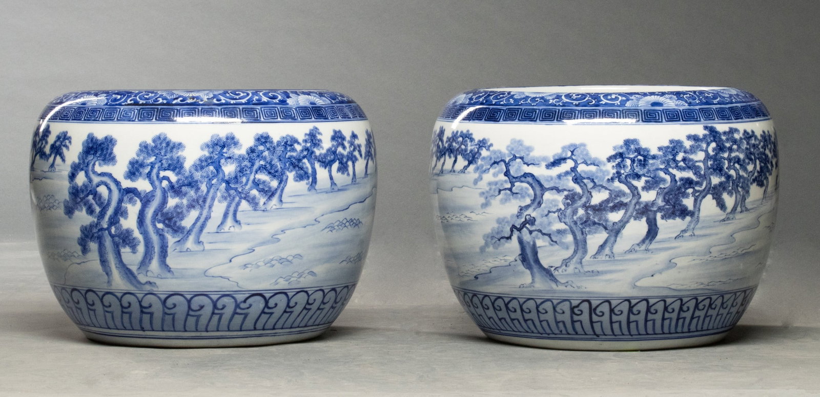 SCARCE EARLY 20TH C. JAPANESE BLUE & WHITE HIBACHI PAIR: The similar pair of large hand painted blue and white porcelain hibachis are decorated in similar cobalt on white landscapes. Mr Adair describes them as follows: A pair of blue and white ceramic hibac
