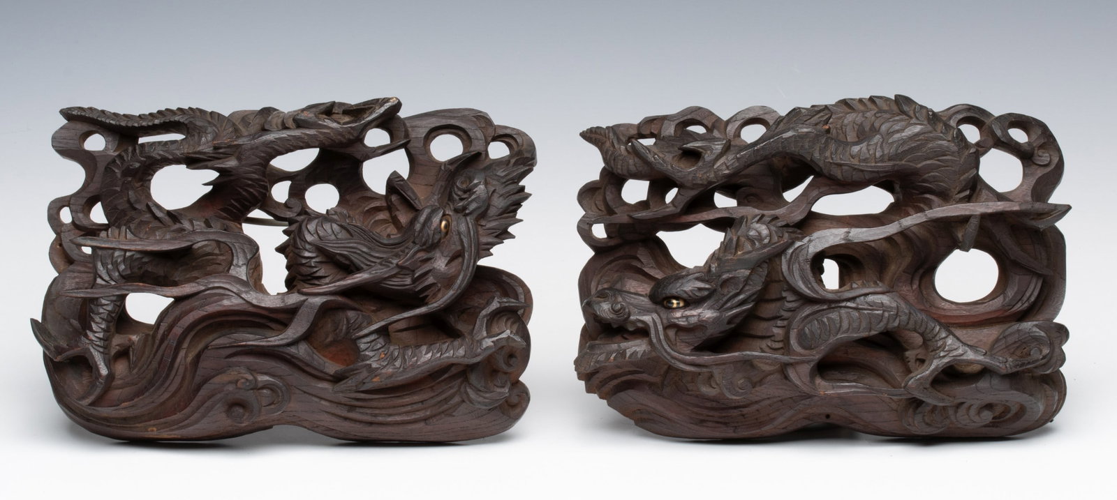 A PAIR OF CARVED KEYAKI WOOD DRAGON ARCHITECTURAL PCS: Each is finely detailed, including the dragon's eye detailed in gold. Each measures 7 x 10.25 x 2.25 inches. Provenance: The estate of John Adair Jr. (1942-2025), founder and proprietor of Kurofune