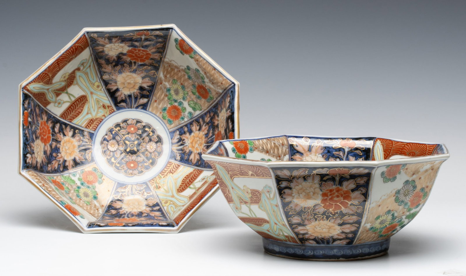 A PAIR MEIJI JAPANESE OCTAGONAL PORCELAIN IMARI BOWLS: The matched pair of deep octagonal bowls feature a central circular medallion of scrolling florals, the sides divided into eight radiating wedge-shaped panels. Each measures 4 x 9.5 inches in diameter