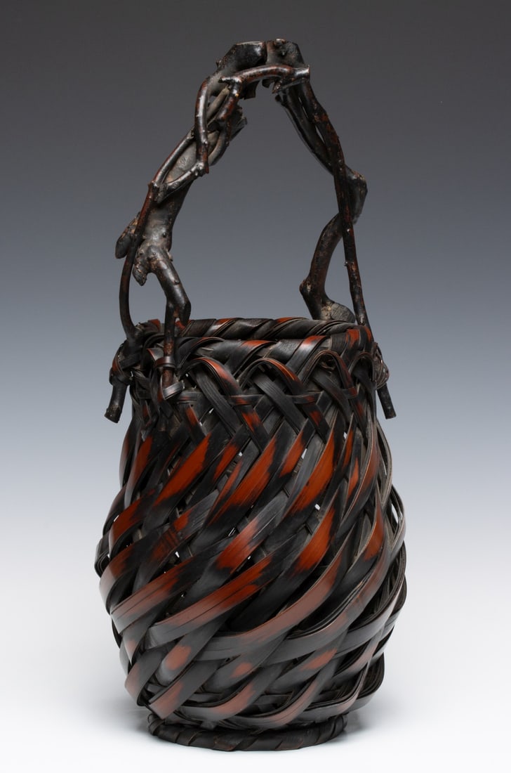 JAPANESE ROOTWOOD & BAMBOO IKEBANA BASKET, ADAIR ESTATE: The tapering globular form is woven in a diagonal plaiting technique creating a swirling effect around the vessel body below a dramatic natural-root (rhizome) handle of gnarled and knotted bamboo. The
