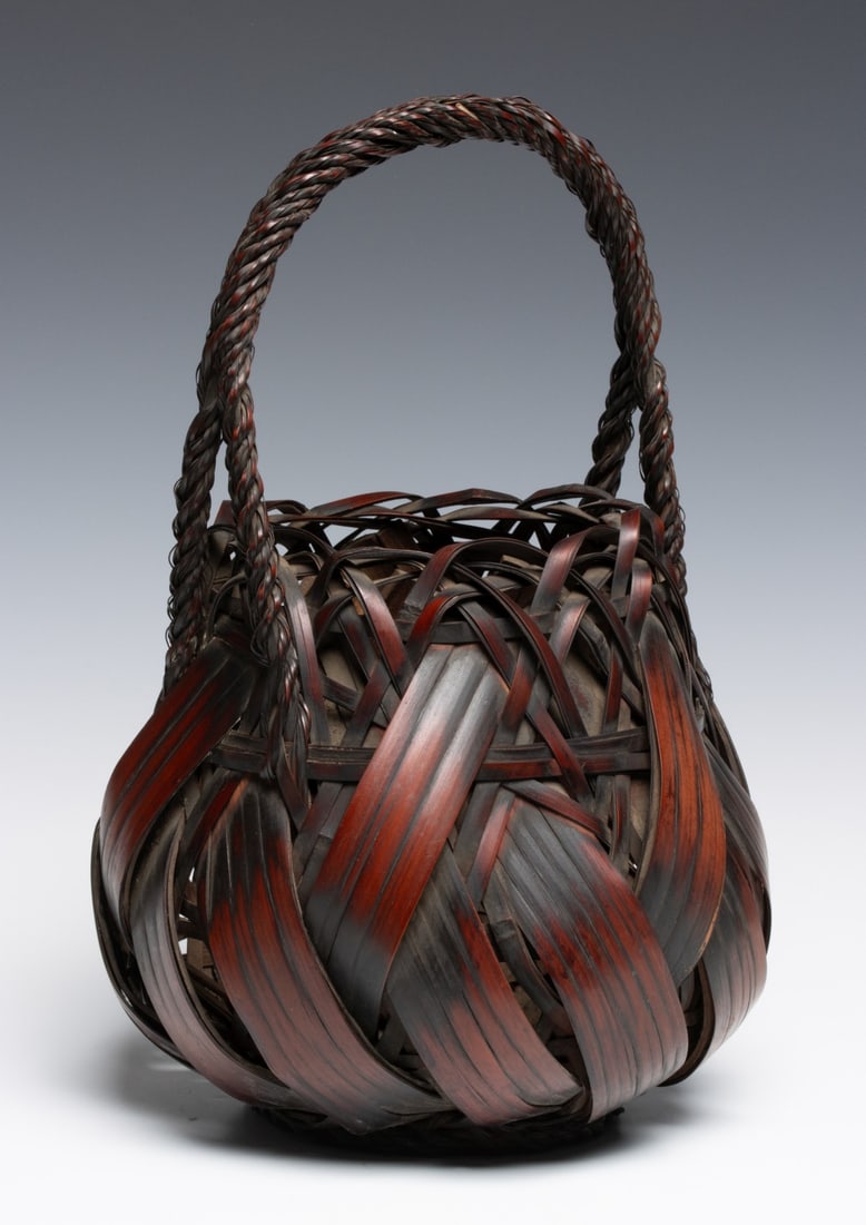 WIDE SPLINT ROPE TWIST JAPANESE HANAKAGO, ADAIR ESTATE: The wrapped and woven body in rich smoked colors incorporates a high arching braided handle, good patina, unsigned. Measures 14.75 x 9 inches in diameter. Provenance: The estate of John Adair Jr.