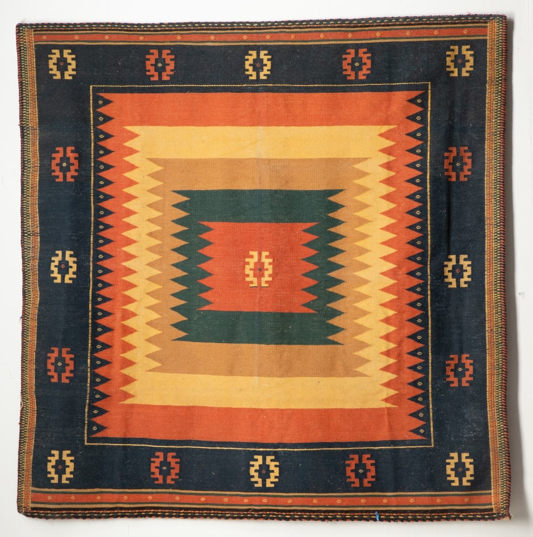 A MODERN CENTRAL TURKISH KILIM,: of square form, with a layered pastel polychrome field within a blue border enclosing continuous alternating ivory and ginger stepped medallions. Measures approximately 57 x 55 inches; 4ft.9 inches