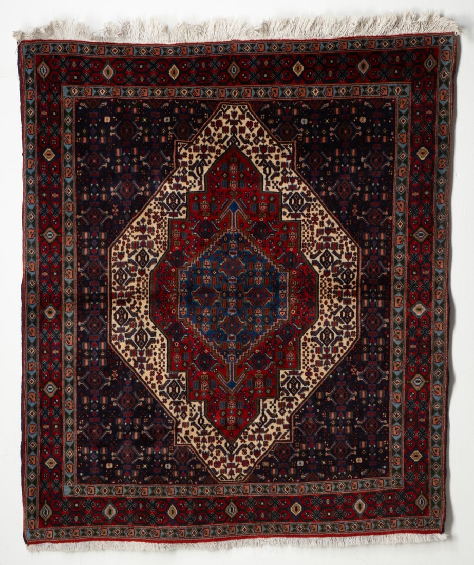 A SENNEH (SANANDAJ) RUG, LATE 20TH CENTURY: the blue field with a layered ivory, red and pale blue stepped medallion, all with 'herati', within a red border enclosing continuous flower heads linked by meandering angular vines. Measures