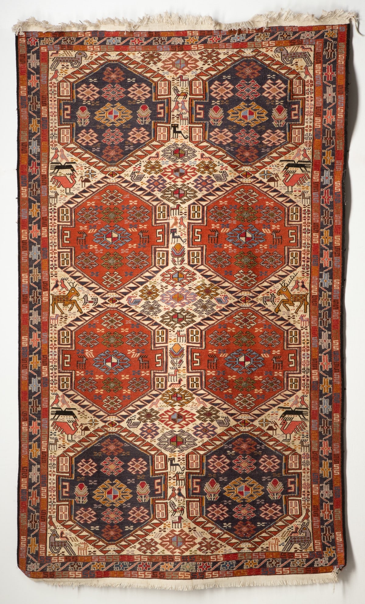 A SHAHSEVAN SOUMAK, 20th CENTURY.: the ivory field with two columns of four stepped and pointed medallions all with a mass of hooked medallions, flower heads,animals and birds within a blue star flower head and meandering vine border.