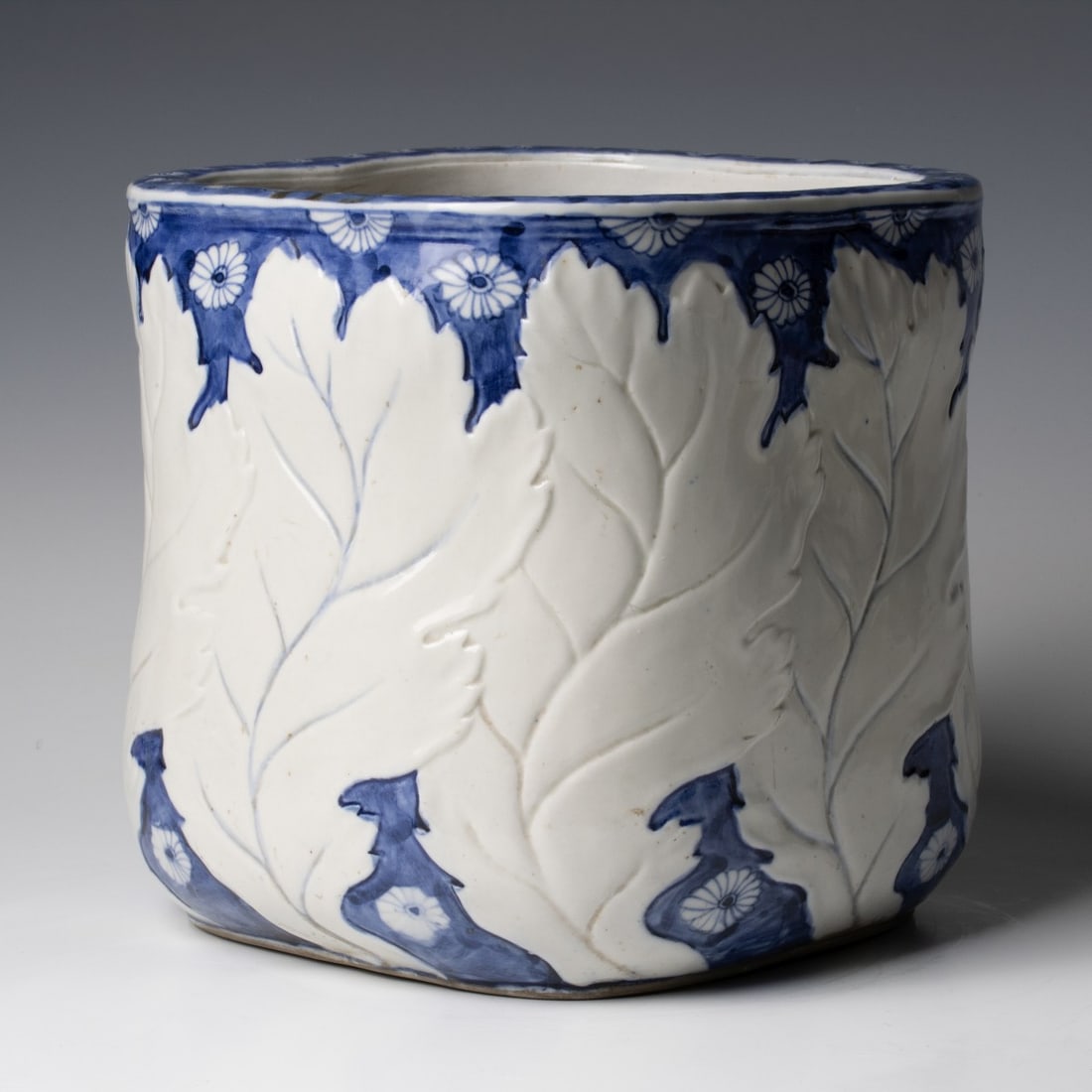 A MEIJI JAPANESE RELIEF MOLDED SQUARE FORM HIBACHI: Probably Arita kiln, large leaves in relief on cobalt ground. Measures 12 x 20 inches in diameter. Provenance: The estate of John Adair Jr. (1942-2025), founder and proprietor of Kurofune Antiques,