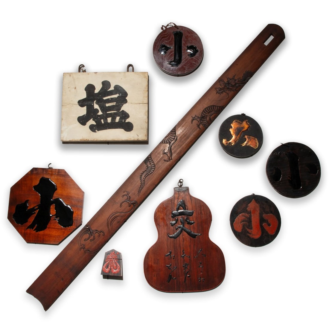 A COLLECTION OF JAPANESE CARVED WOOD MERCHANT SIGNS: Eight carved wood signs, as shown, plus an additional carving with a highly detailed writhing dragon. Sizes range from 3.25 to 60.75 inches in length. Provenance: The estate of John Adair Jr. (1942-20