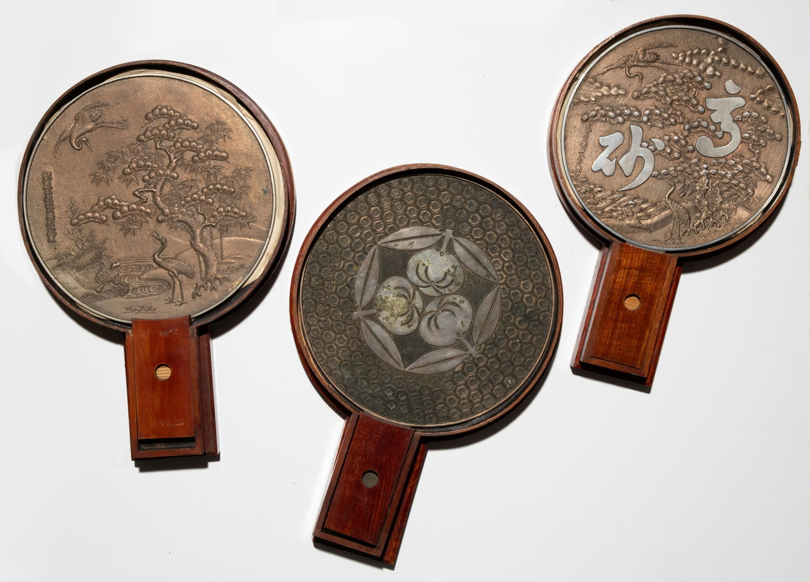 THREE JAPANESE BRONZE HAND MIRRORS IN KEYAKI WOOD CASES: Three fine examples as shown. Sizes range from 13.75 x 9.25 to 15.25 x 10.25 inches. Provenance: The estate of John Adair Jr. (1942-2025), founder and proprietor of Kurofune Antiques, Tokyo (est. 1978