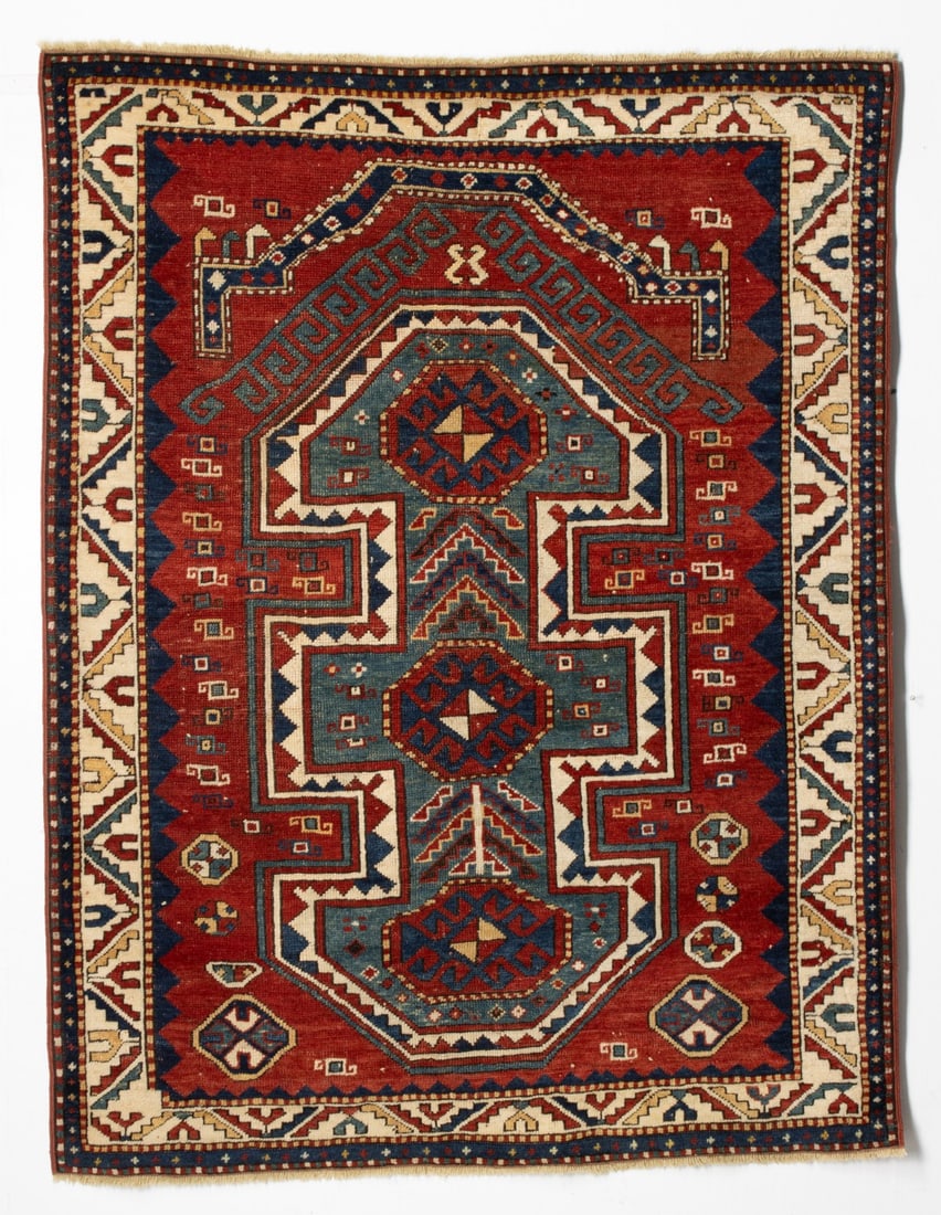 FINE UNUSUAL KAZAK SEWAN RUG, LAST QUARTER 19TH C: The red field with a central blue/green stepped and pointed reserve enclosing three octagonal red medallions linked by serrated chevron leaf adorned plants, supported by hooked squares and octagonal f