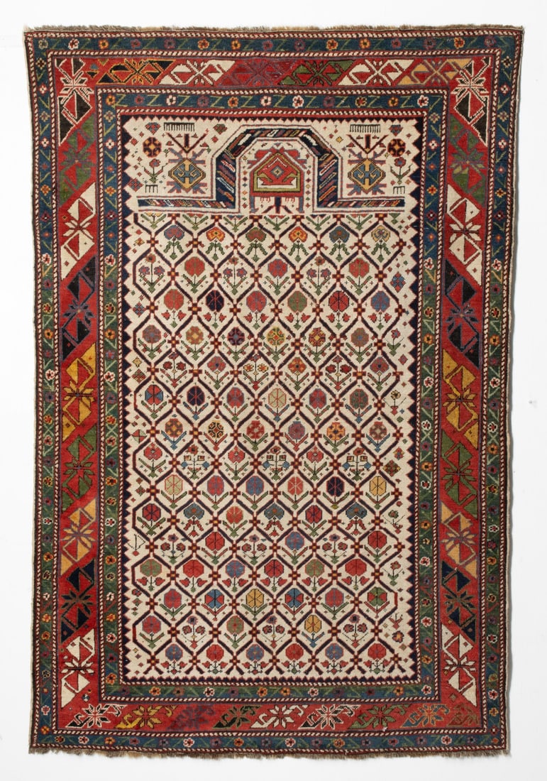FINE SHIRVAN PRAYER RUG, EAST CAUCASUS, CIRCA 1875: The ivory mihrab with an allover linked leaf lattice enclosing offset rows of polychrome multifarious plants below a chamfered flattened arch enclosing a pentagonal medallion, ivory palmette, flower h