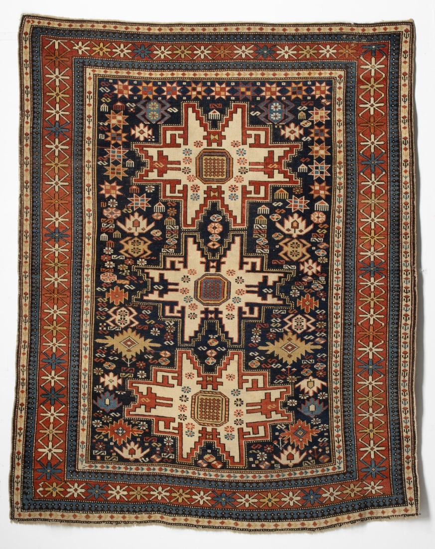 LESGHI RUG, EAST CAUCASUS, CIRCA 1880: The blue field with a column of three large 'Lesghi' stepped medallions supported by polychrome star flower heads, palmettes, flower heads and jewelry, within a red cruciform flower head border,
