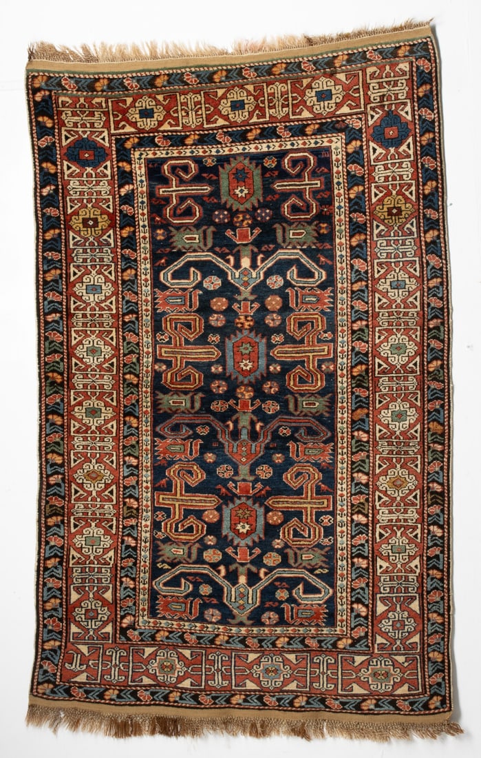 FINE PEREPEDIL RUG, EAST CAUCASUS, CIRCA 1880: The blue field with three serrated rectangular medallions supported by rams horns, pairs of birds and scattered flower heads within a red rosette, bracket vine kufic border. Measures approximately 73 