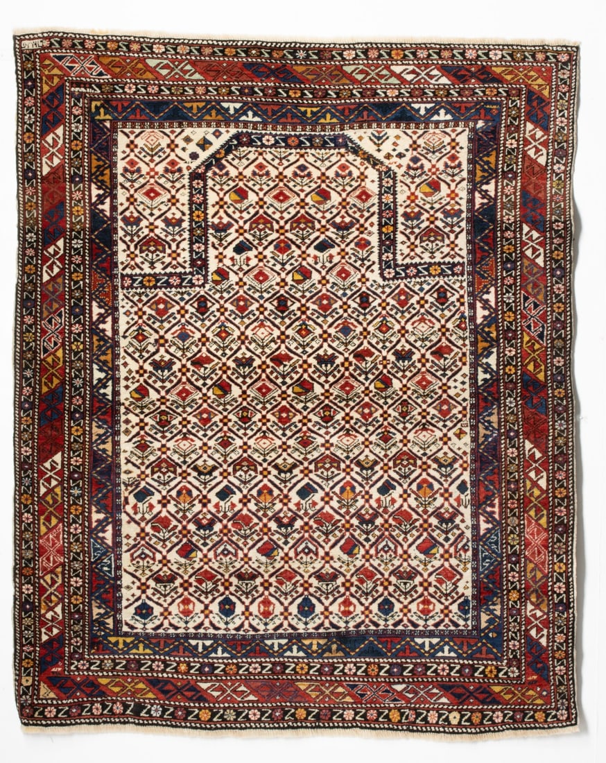 FINE DAGHESTAN PRAYER RUG, DATED AH 1277/AD 1860: The ivory mihrab with an allover leaf lattice enclosing offset rows of multifarious polychrome flowering plants below a chamfered flattened arch, similar spandrels, within a red border enclosing conti