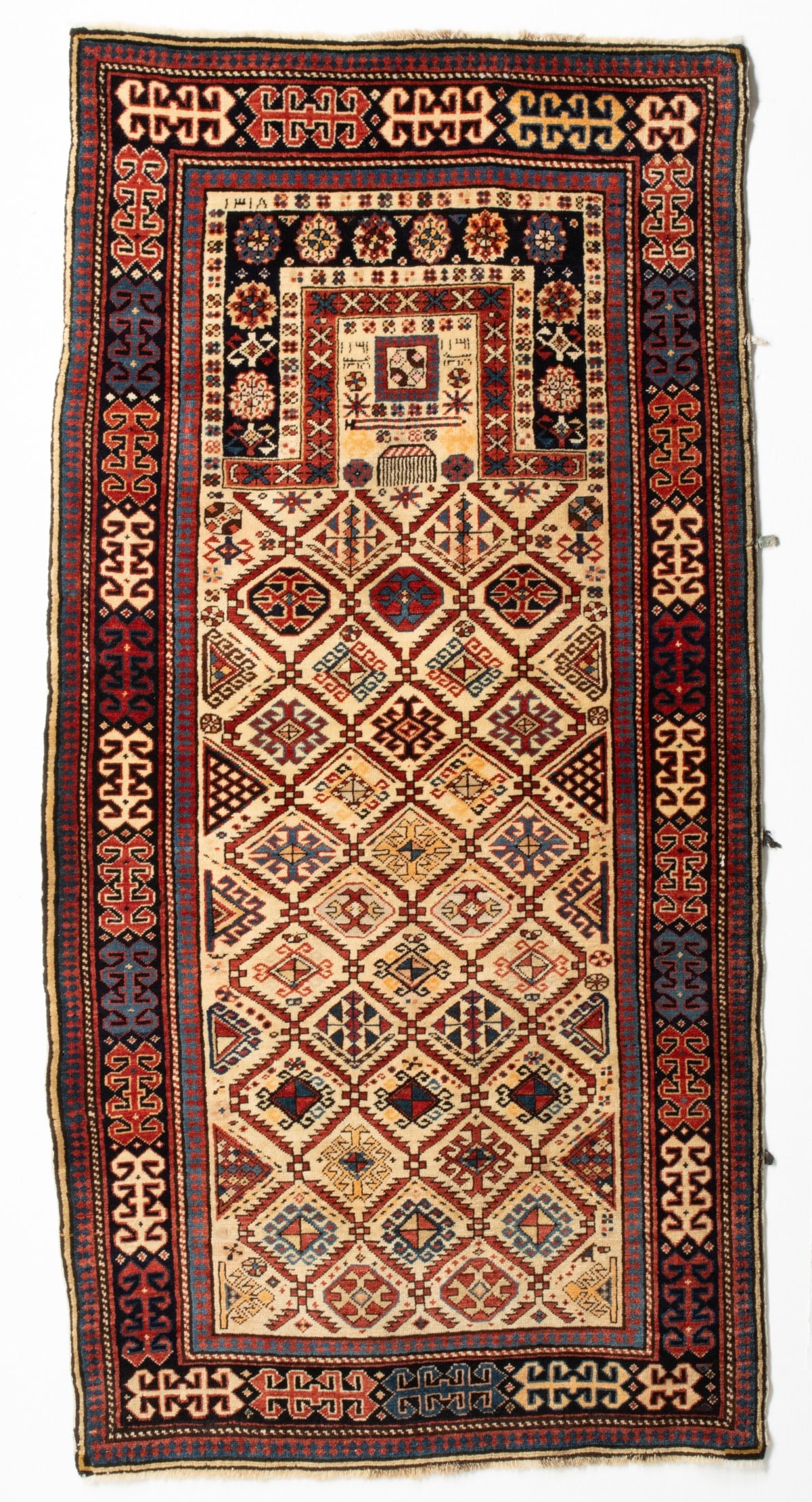 FINE AKSTAFA PRAYER RUG, DATED AH1318/1900 AD: The ivory mihrab with a serrated leaf lattice enclosing a variety of finely drawn hooked and stepped medallions below a comb dais, a square medallion mirrored number inscriptions within a square forme