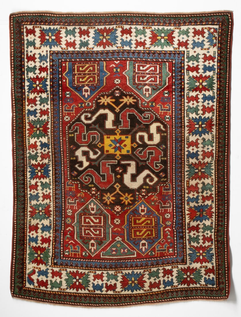 FINE KAZAK CHONDZORESK RUG, CIRCA 1875: The abrashed red field with a charcoal hexagonal medallion with a rectangular saffron centrepiece, surrounded by alternating ivory and red cloud bands, supported by hexagonal cartouches scattered anim