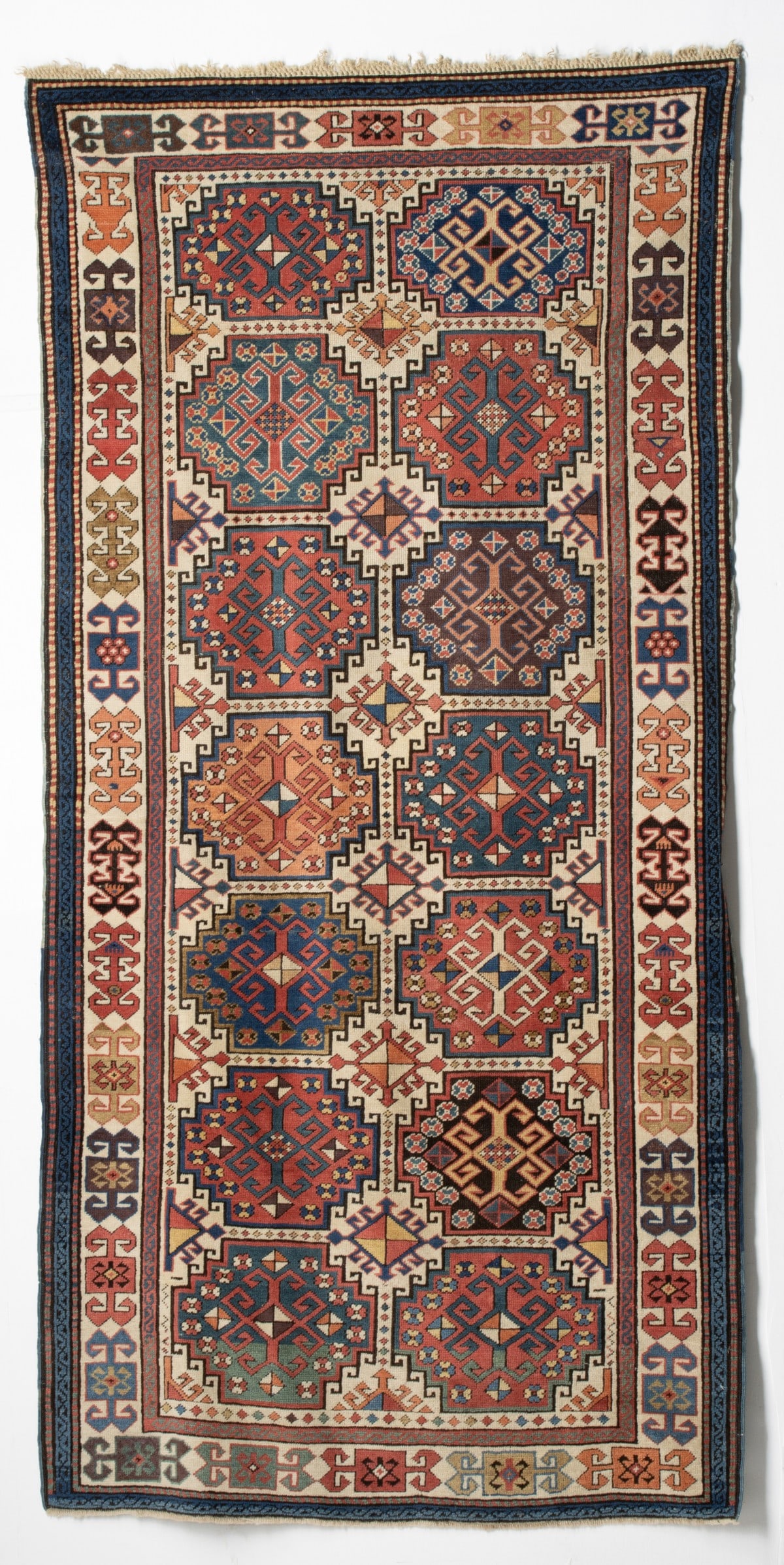 FINE AKSTAFA RUG, EAST CAUCASUS, CIRCA 1870: The ivory field with two columns of seven stepped and hooked 'Memling' guls, each enclosing a hooked rhombus lozenge and flower heads, flanked by a central column of hooked rhombus medallions, within 