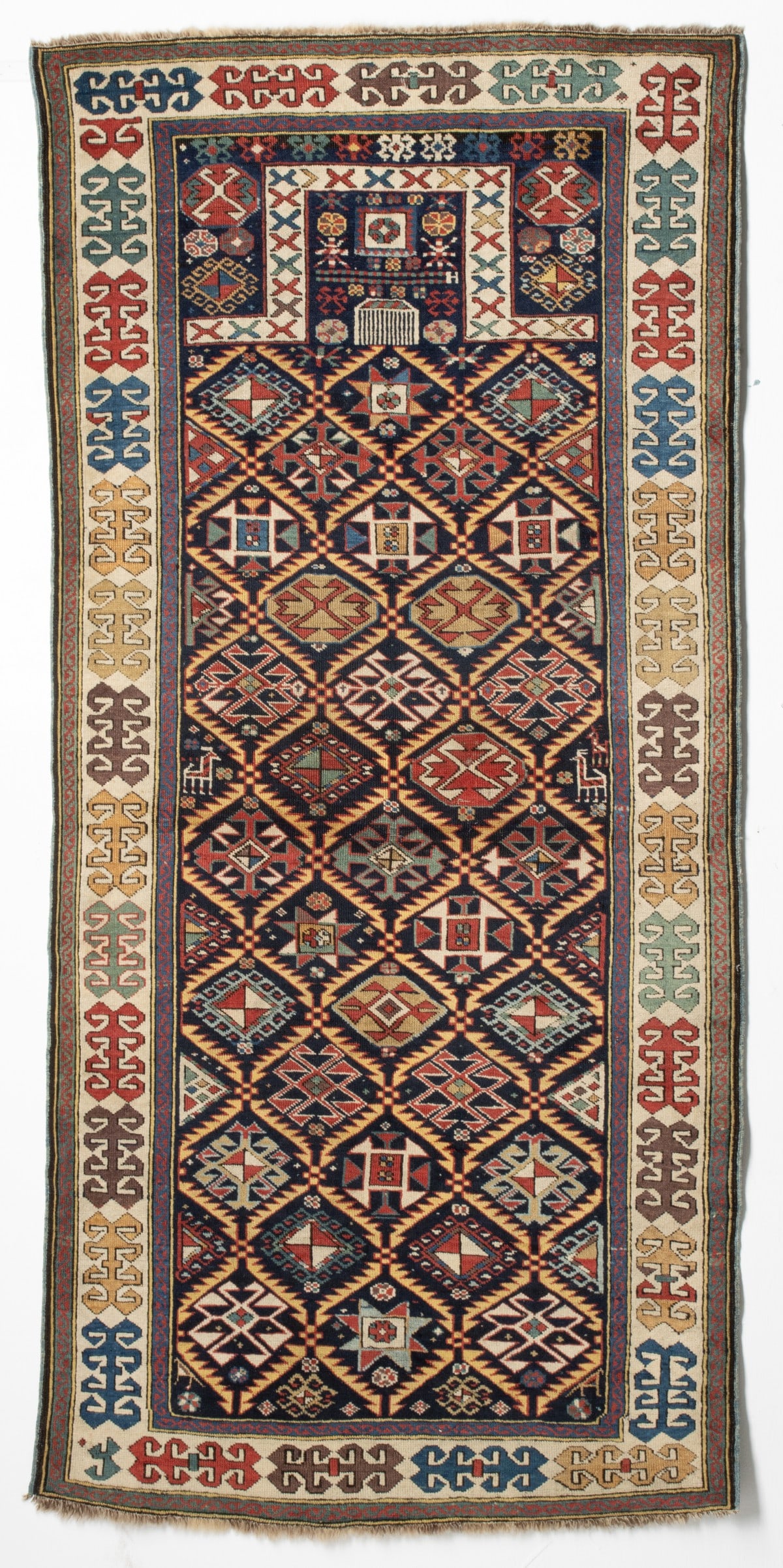 FINE AKSTAFA PRAYER RUG, THIRD QUARTER 19TH CENTURY: The blue mihrab with a serrated leaf lattice enclosing rows of multifarious medallions below a flattened arch enclosing a comb dais and small flora forms, blue hooked medallion spandrels within a cont