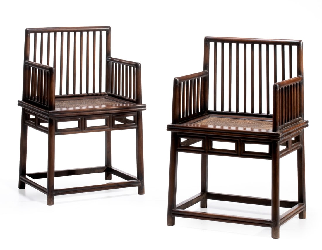 A PAIR LATE QING DYNASTY CHINESE SPINDLE BACK ARMCHAIRS: A fine pair of Chinese spindle-back armchairs, in Huanghali type hardwoods featuring a straight crest rail over a backrest with ten slender vertical spindles. The straight, un-protruding armrests with
