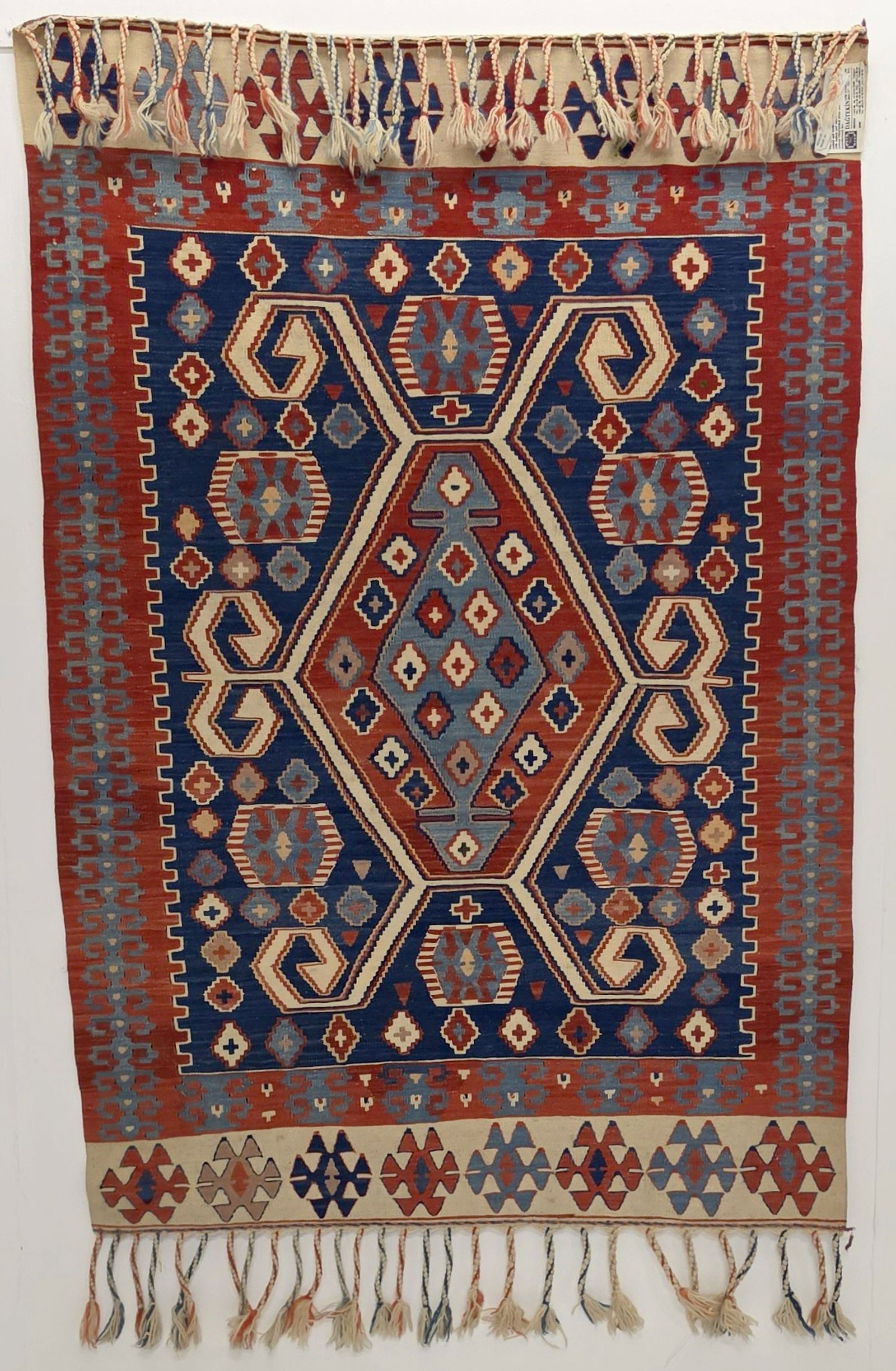 A FINE MODERN TURKISH KELIM, CENTRAL TURKIYE: The red, white and blue kelim with latch hooked hexagonal lozenge medallion is framed by a red border and ivory banded ends. Measures approximately 63 x 43 inches; 5ft.3 inches x 3ft.7 inches. Provena