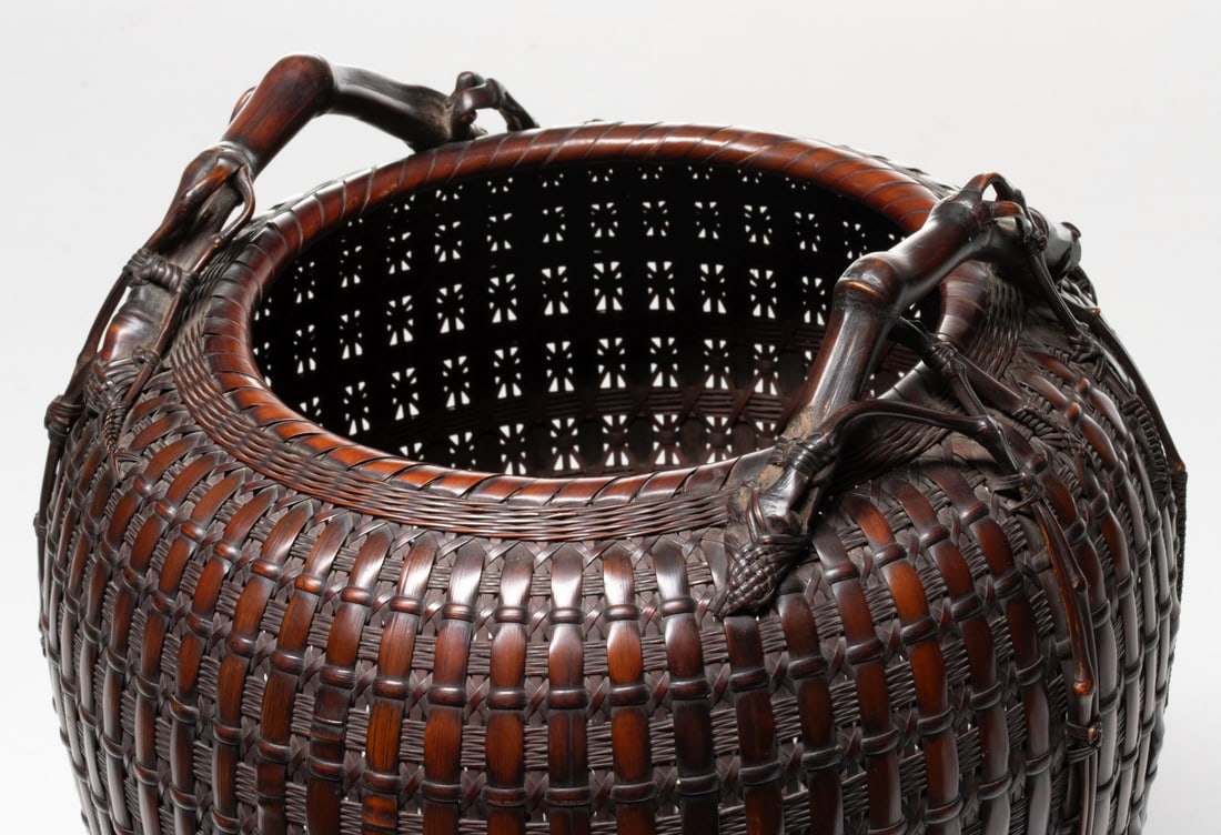 TANABE CHIKUUNSAI ROOT HANDLE BASKET, ADAIR ESTATE: The outstanding example of high-shouldered ovoid form is woven using a dense plain square weave overlaid with thick, vertical reinforcing to a body that tapers toward the recessed corded foot. The ver