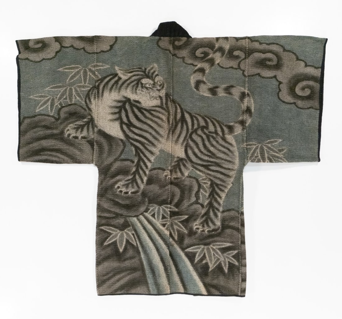 JAPANESE FIREMAN'S COAT WITH TIGER, ADAIR ESTATE: The rare 19th century 'firefighter's' coat, made by hand stitching together multiple layers of loomed cotton fabric using thousands of sashiko stitches, features a tiger on rocky craig with bamboo and