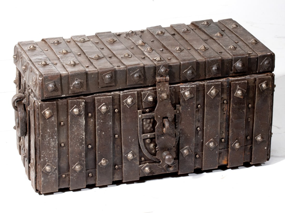 AN INTERESTING 18TH C. CONTINENTAL IRON BOUND STRONGBOX: The forged and riveted iron bound box with thick and heavily forged ring handles and hasp has a heraldic shield-like device in ron front side behind the hasp an ring. Measures 13 x 27.5 x 12 inches. P