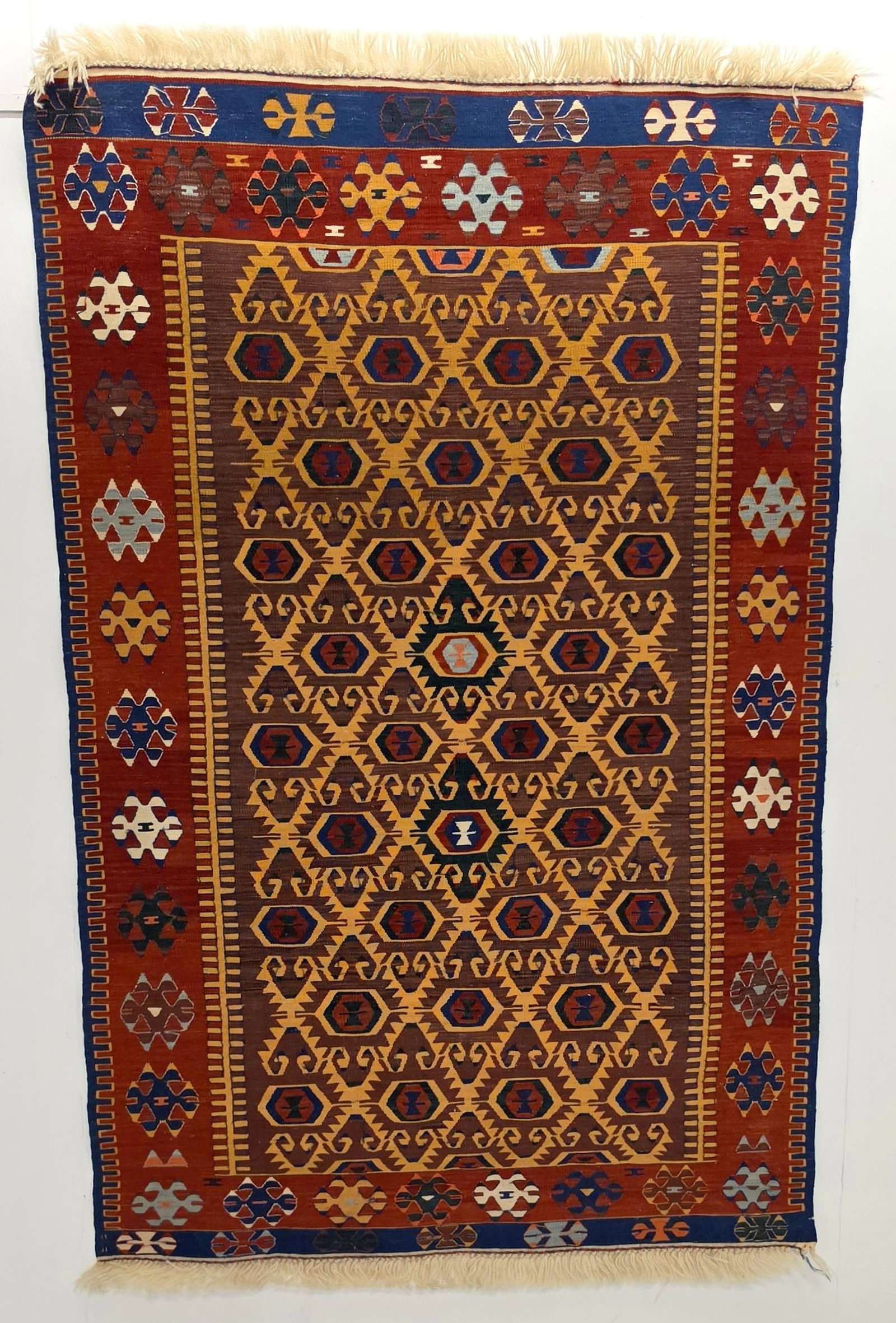A FINE MODERN TURKISH KELIM, CENTRAL TURKIYE: With overall gold lattice on plum brown field within a red border enclosing ram-horn rosettes. Measures approximately 70 x 46 inches; 5ft.10 inches x 3ft.10in; 178 x 117cm. Provenance: The estate of J