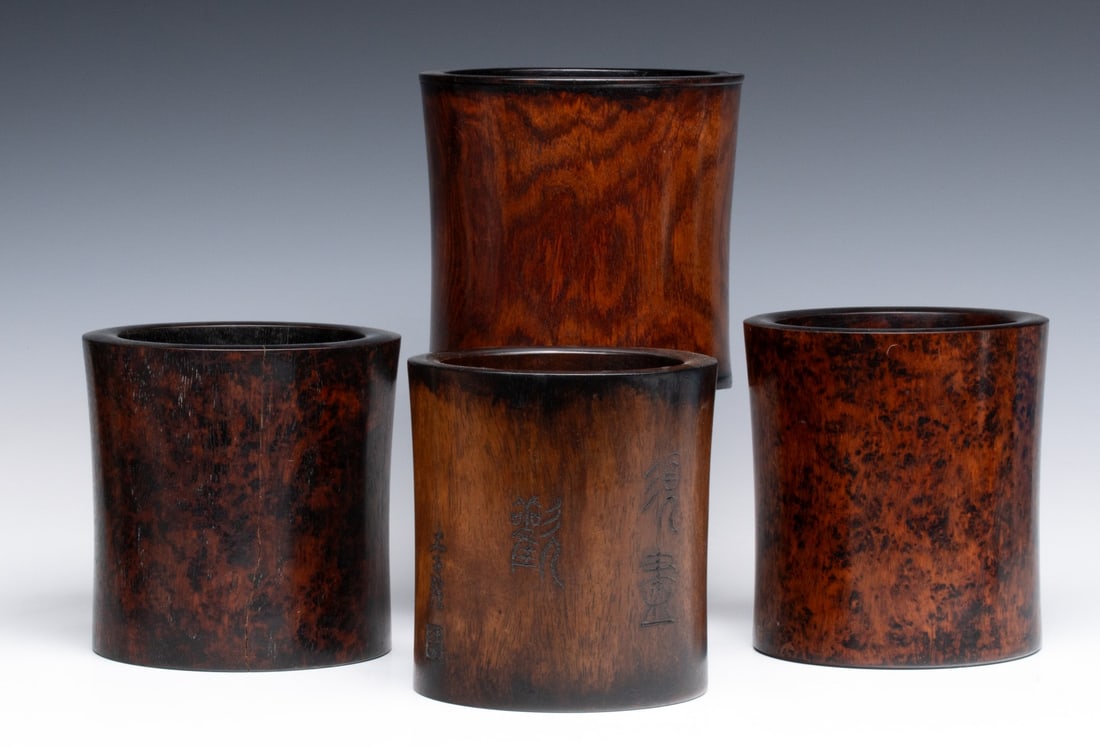 FOUR ANTIQUE CHINESE HUANGHUALI TYPE BRUSH POTS: Three highly figured wood brush pots with good patina and a fourth with engraved inscriptions, three with original inserts. Sizes range from 6.25 x 5.75 to 6.5 x 6.5 inches. Provenance: The estate of 