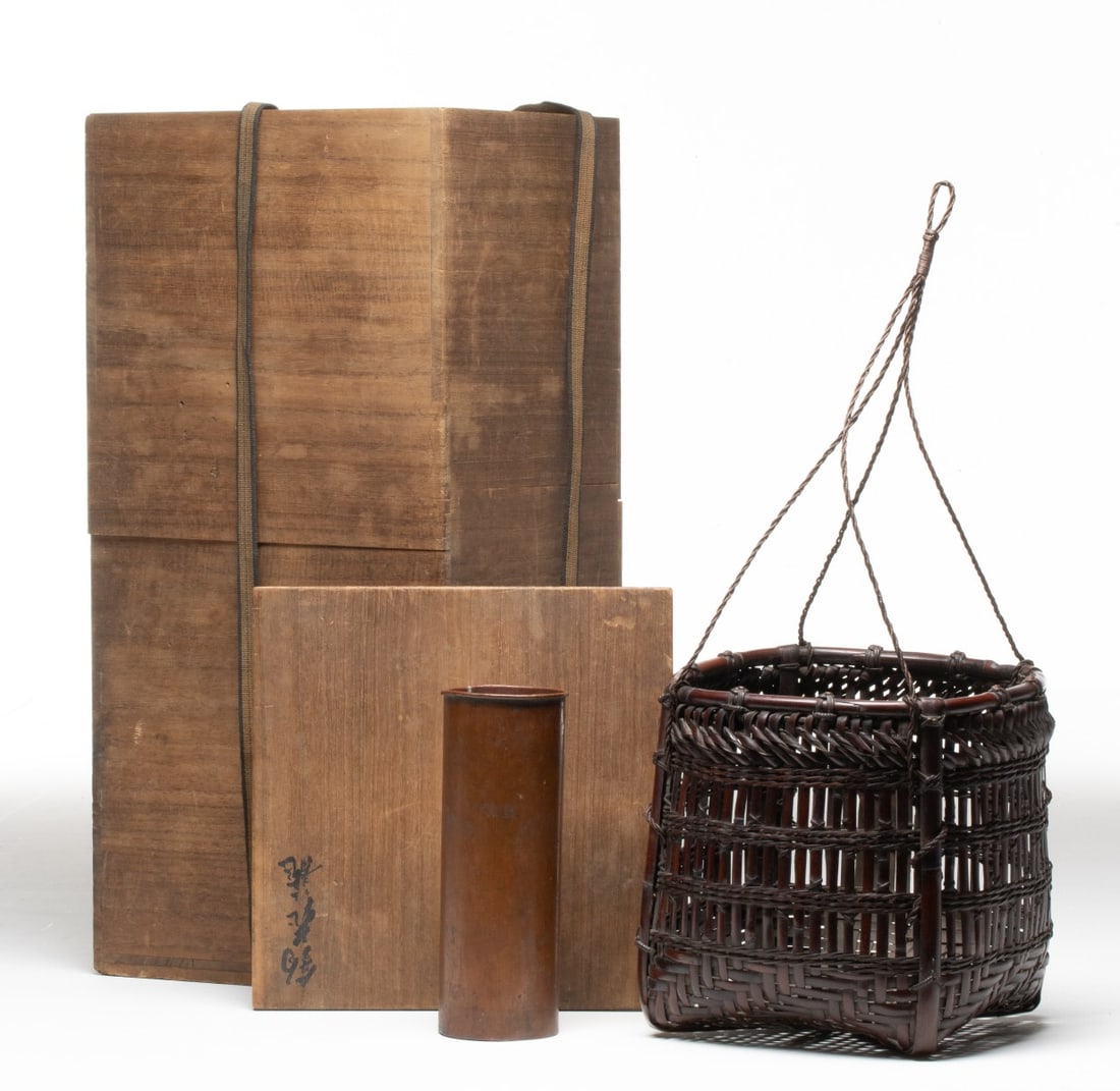 WADA WAICHISAI III JAPANESE BAMBOO BASKET, ADAIR ESTATE: The unusual hanging basket for ikebana features a square base that transitions into a cylindrical body using an airy open-work of vertical plaiting punctuated by horizontal bands of braided rope-weave
