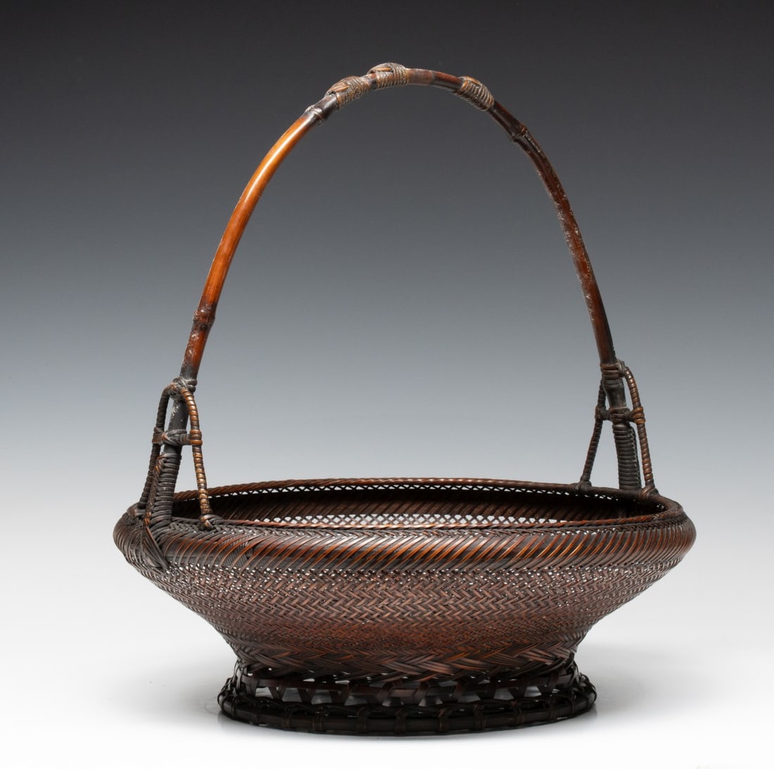 A JAPANESE BAMBOO BASKET OF FINE DETAIL, ADAIR ESTATE: A very fine example with great patina, featuring a shallow body with rounded shoulder that rolls inward to a precisely woven line of openwork encircling the upper rope-twist rim. The body is rendered 