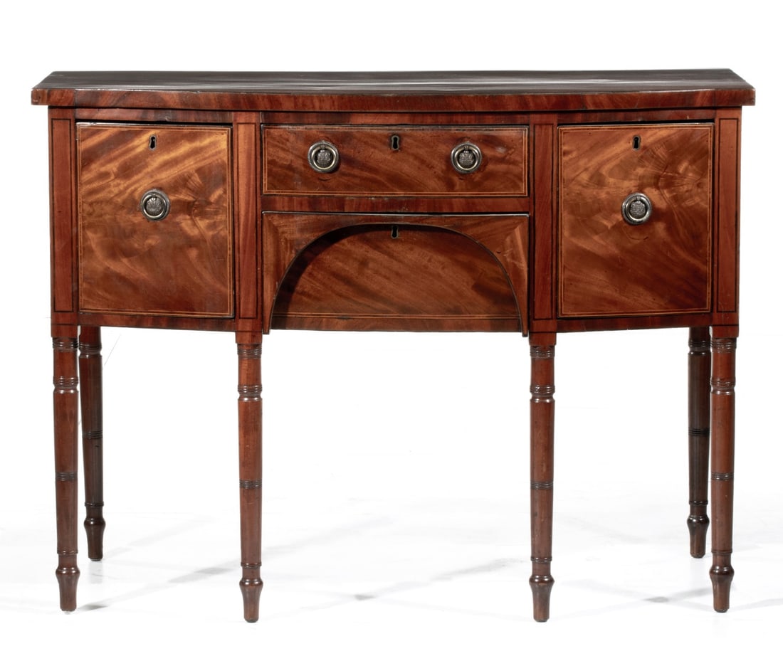 AN EARLY 19TH C. SHERATON SIDEBOARD OF DIMINUTIVE SIZE: The one-board mahogany top overhangs one handled drawer and one hidden drawer, each end is fitted with a deep bottle drawer. Measures 36 x 48 x 23.5 inches. Provenance: The estate of John Adair Jr. (1