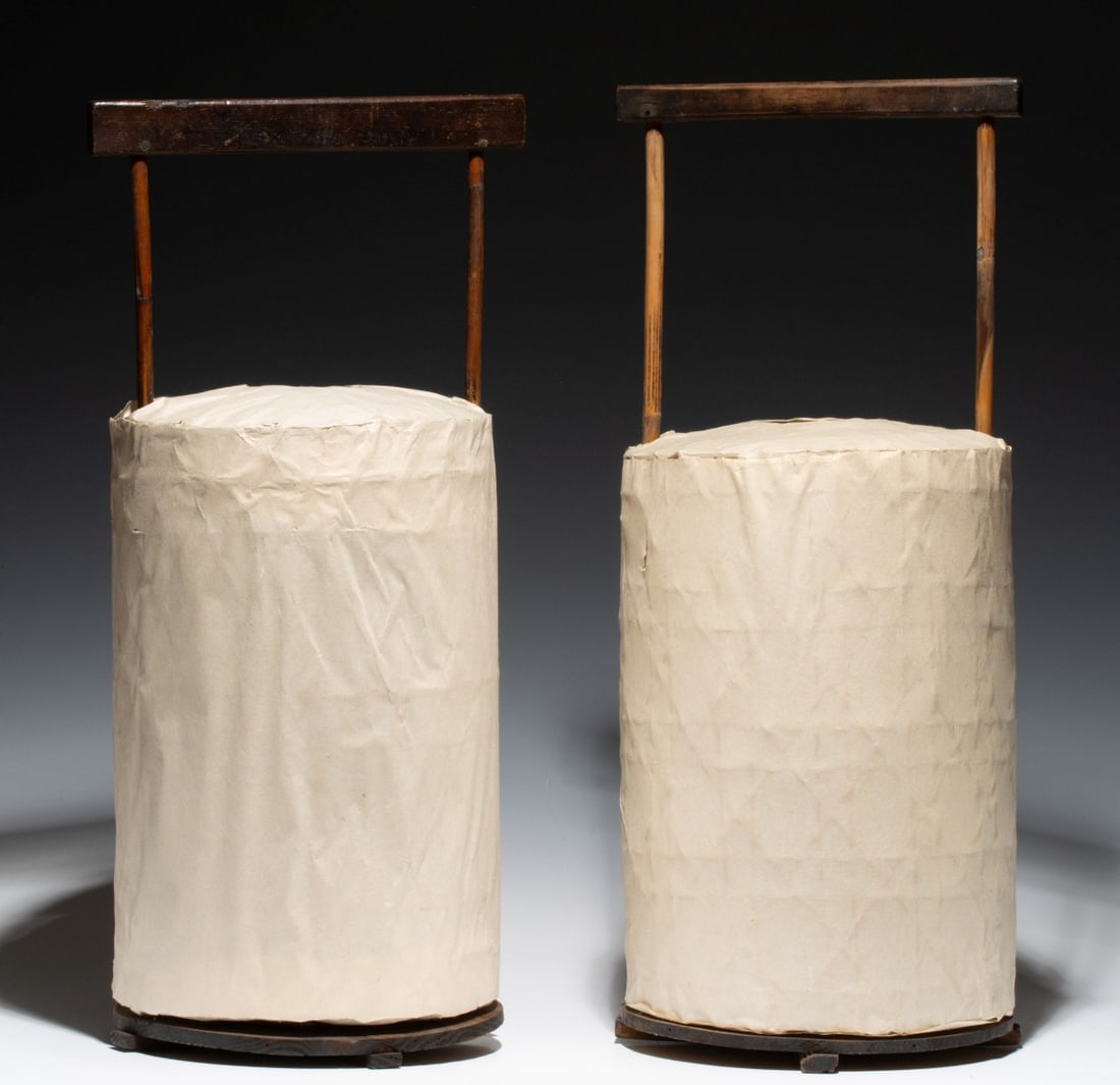 A PAIR MEIJI PERIOD WOOD AND WASHI PAPER HAND LANTERNS: Each lantern is designed as a cylindrical silhouette of hexagonal split bamboo basketweave frame wrapped in thick cream-colored handmade washi (mulberry) paper. When lit, the paper stretched over the 