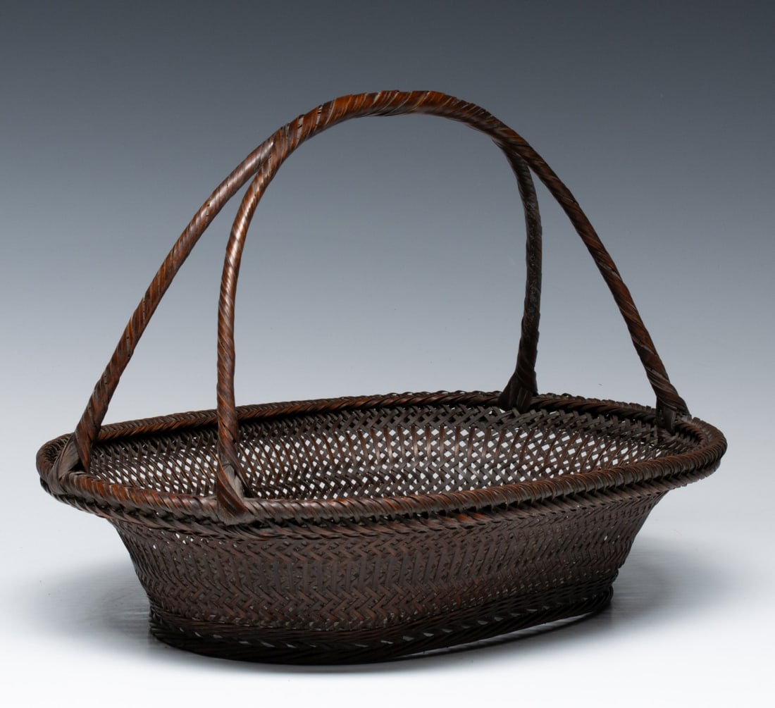 AN ARTIST-SIGNED JAPANESE IKEBANA BASKET, ADAIR ESTATE: The fine example attributed to Yamamoto Shoun (1911-1973) features a wide, low-profile oval body woven in a precise twill weave that transitions to an open-work hexagonal mesh at the center of the bas