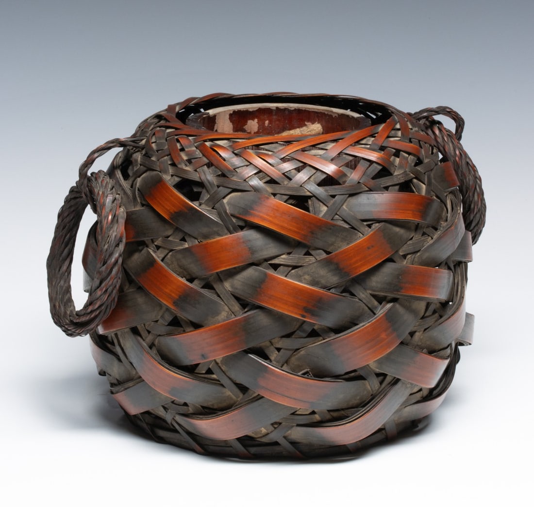 A JAPANESE BASKET WITH COILED HANDLES, ADAIR ESTATE: The globular form of overlapping and crosshatched splints has coiled and twisted ring bamboo handles either side, and a tubular bamboo insert. Measures 8 x 9 x 9 inches. Provenance: The estate of John