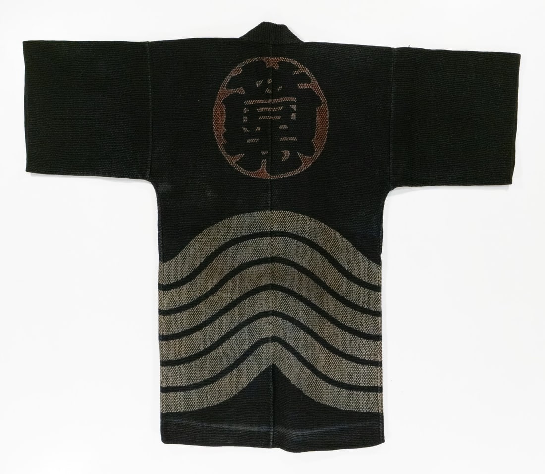 SIGNED JAPANESE FIREMAN'S COAT WITH CREST, ADAIR ESTATE: The rare 19th century firefighter's jacket is constructed of multiple layers of indigo-dyed cotton densely secured with thousands of sashiko stitches. An actual firefighter's jacket, the back displays