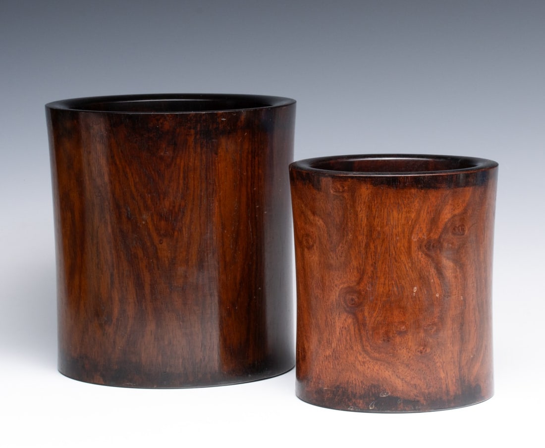 TWO ANTIQUE CHINESE HUANGHUALI TYPE BRUSH POTS: Two wood brush pots with good patina and closely matched, in graduated sizes, each with original inserts. Measures 6.75 x 6 and 8 x 7.75 inches. Provenance: The estate of John Adair Jr. (1942-2025), f