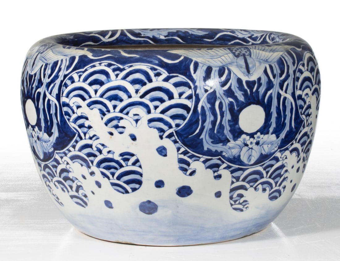 AN EARLY 20C. JAPANESE HIBACHI WITH BIRD AND MOON: The hand painted blue and white porcelain hibachi is decorated with a bird and moon in reverse on cobalt above ocean waves. Measures 11.5 x 17.75 inches in diameter. Provenance: The estate of John Ada
