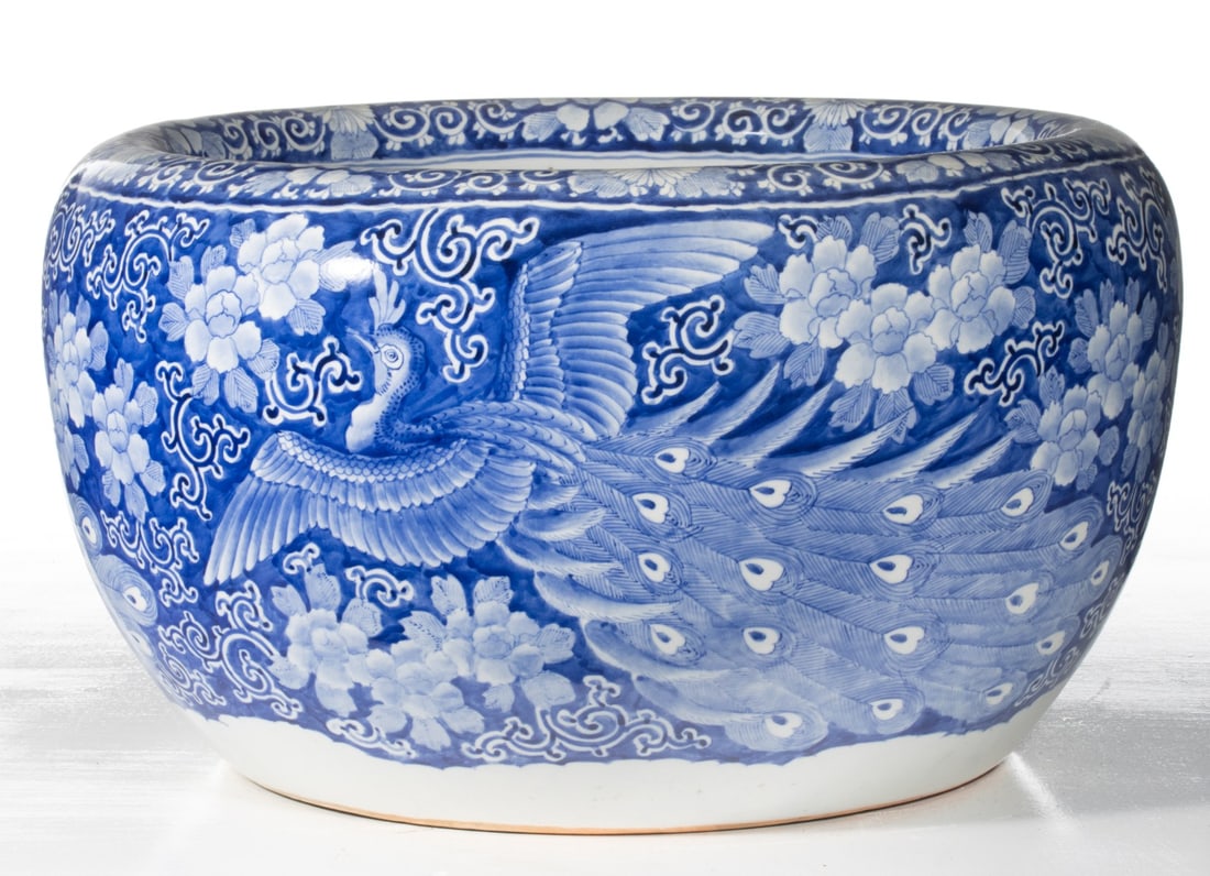 AN EARLY 20C. JAPANESE BLUE & WHITE HIBACHI W/PEAFOWL: The large hand painted blue and white porcelain hibachi is decorated with peafowl in flight among chrysanthemums and scrolls in cobalt on white. Measures 12.5 x 21.25 inches in diameter. Provenance: T