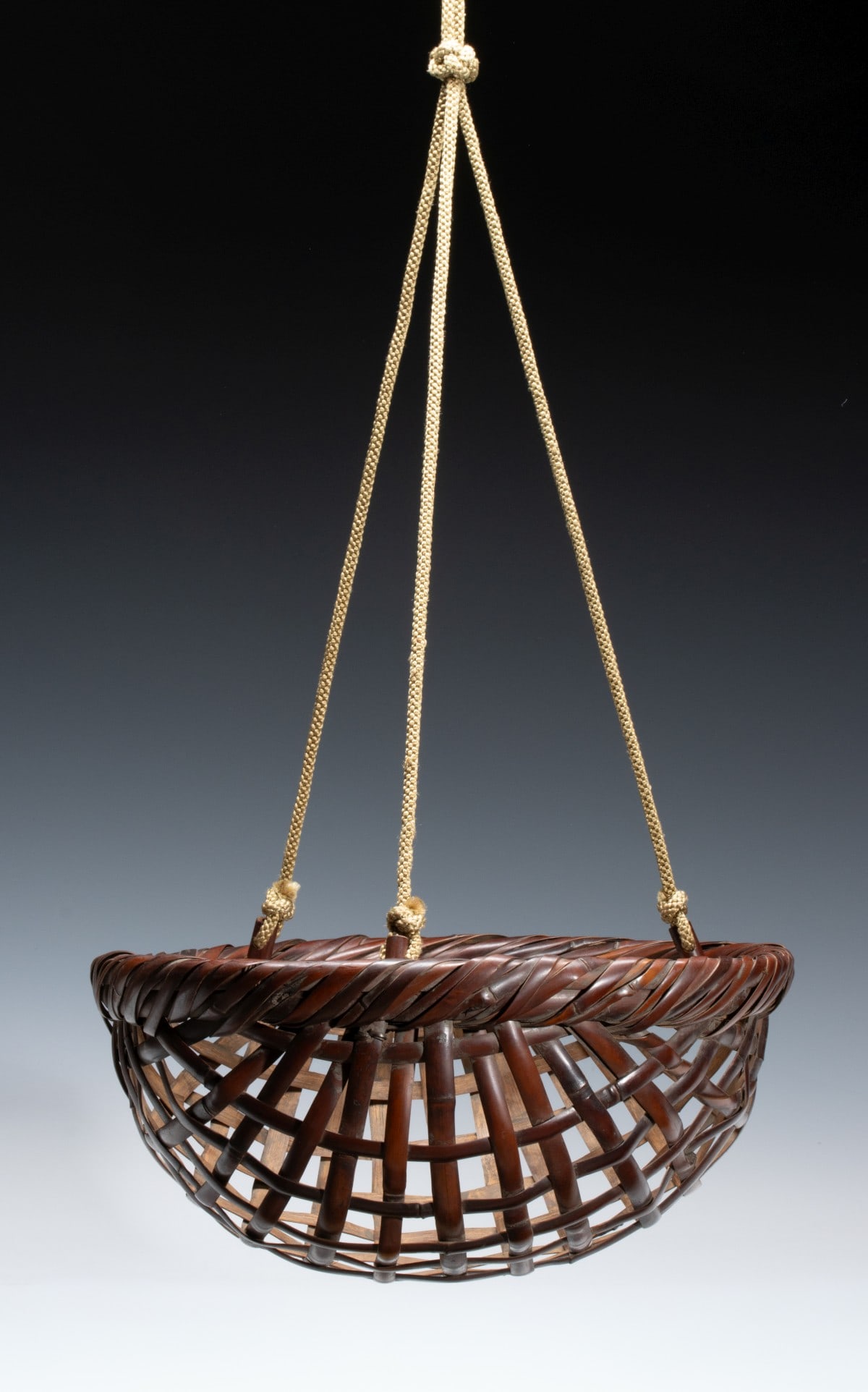 AN UNUSUAL JAPANESE HANGING IKEBANA BASKET ADAIR ESTATE: The unusual example with wide, shallow, semi-hemispherical body is constructed from a robust open-square weave of exceptionally thick, round-edge bamboo woven with airy transparency with geometric