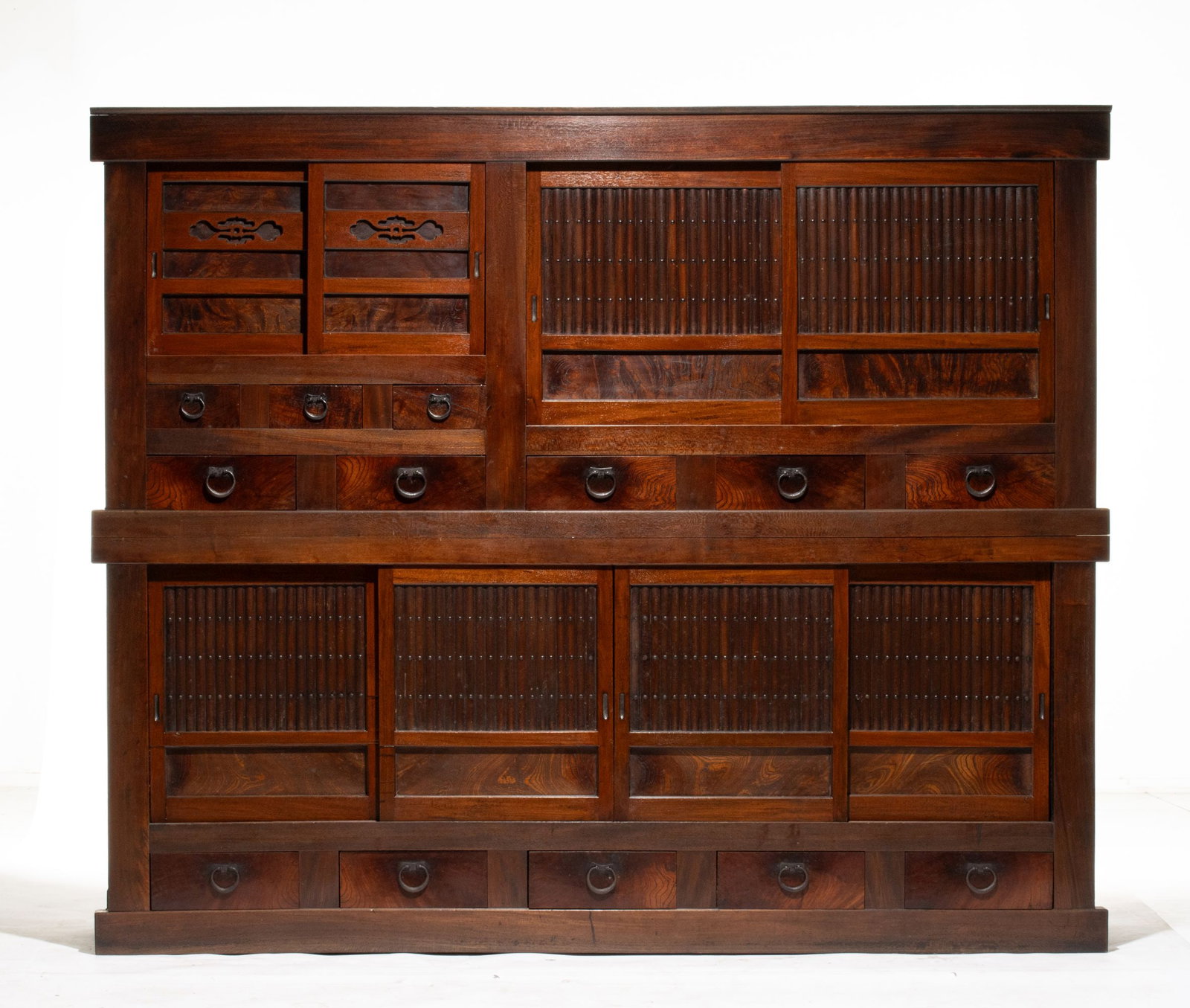 A MONUMENTAL MEIJI JAPANESE KEYAKI WOOD KITCHEN CHEST: The fine and rare region two-piece chest is constructed with cedar frame and keyaki wood front featuring sliding doors over drawers of various sizes with fronts centered by iron pulls. The keyaki hard