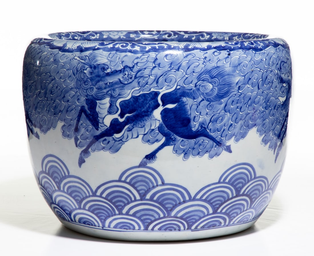 AN EARLY 20C. JAPANESE BLUE & WHITE HIBACHI WITH KIRIN: The large hand painted blue and white porcelain hibachi is decorated in cobalt blue depiction of a soaring mythical Kurin amidst swirling clouds and stylized waves. Measures 11 x 16 inches in diameter