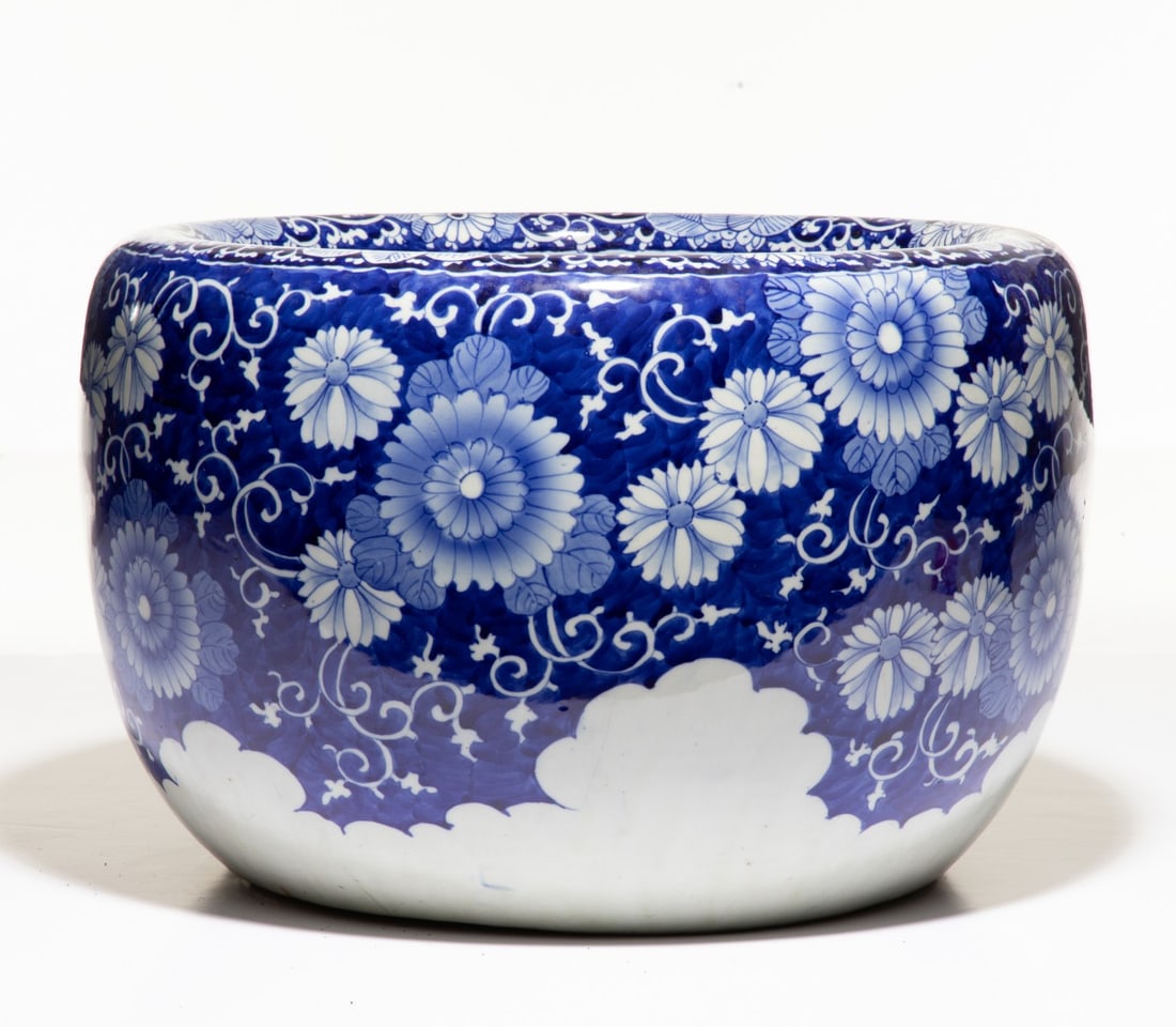 AN EARLY 20C. JAPANESE BLUE & WHITE HIBACHI WITH MUMS: The large hand painted blue and white porcelain hibachi is decorated in chrysanthemum scrollwork against a rich cobalt ground. Measures 11.5 x 17.5 inches in diameter. Provenance: The estate of John A